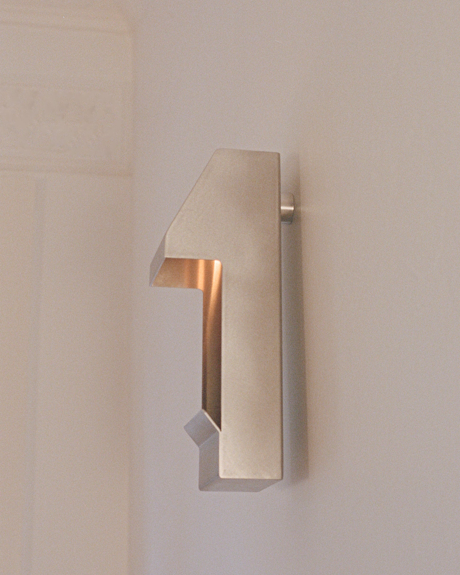 The side of a candle holder by PARCTA with a lit candle inside on a neutral background.