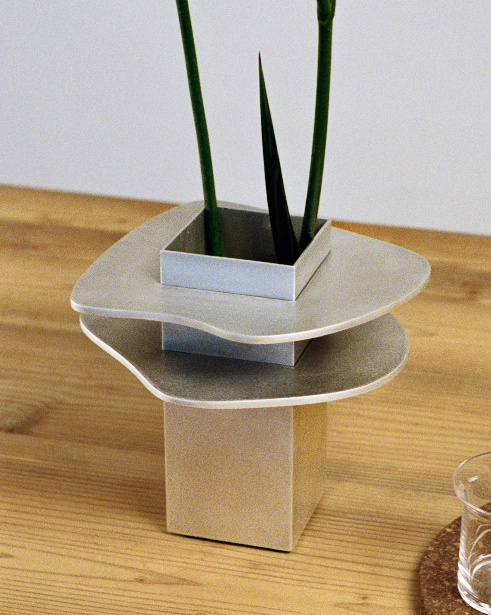 Close up of vase by PARCTA sat on a wooden table with a coaster and glass of water placed besides it.
