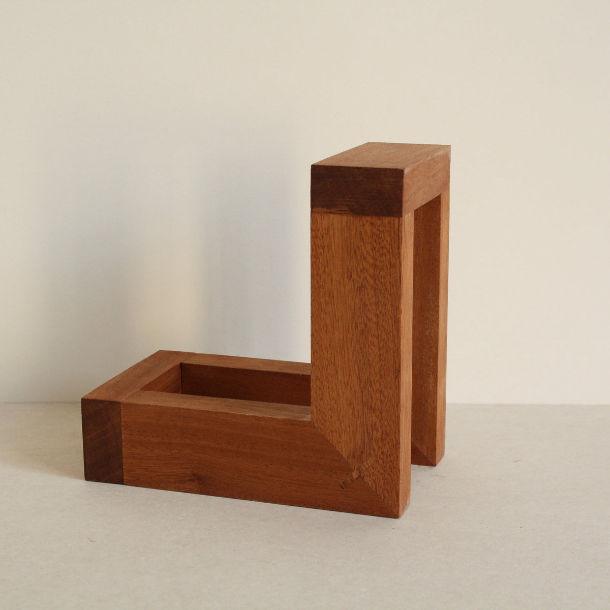 A multipurpose wooden bookend by Evelyn Vanoverbeke on a neutral background.