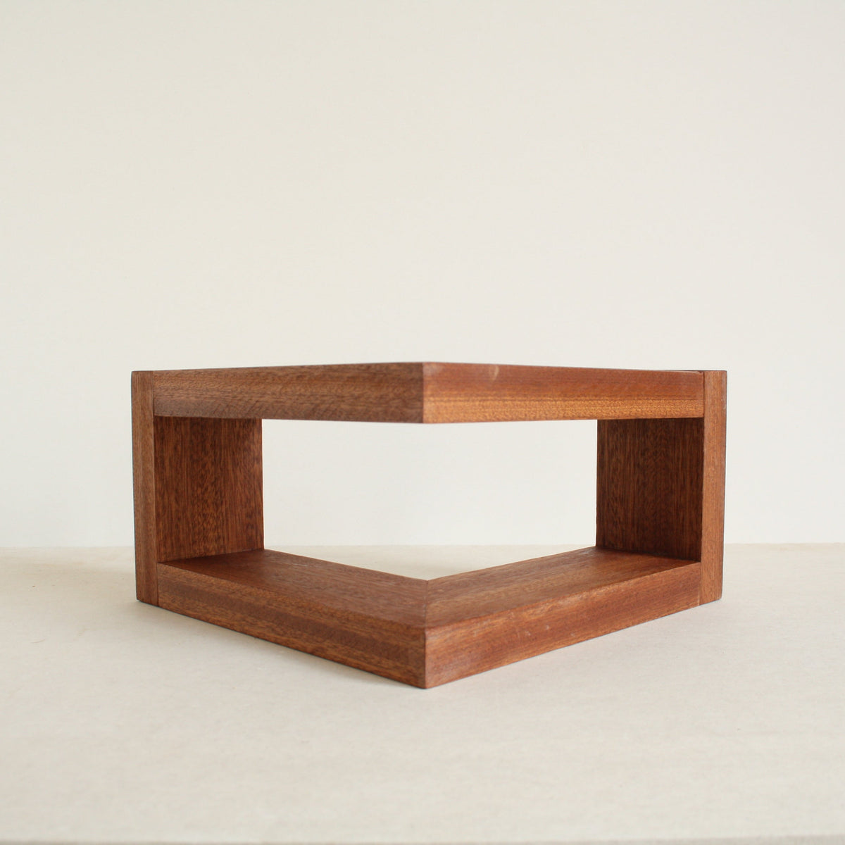 A multipurpose wooden bookend by Evelyn Vanoverbeke on a neutral background.