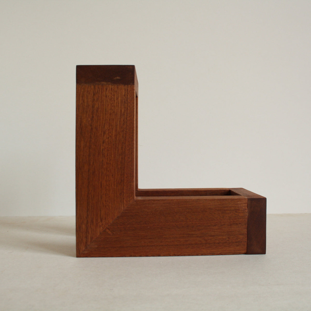A multipurpose wooden bookend by Evelyn Vanoverbeke on a neutral background.