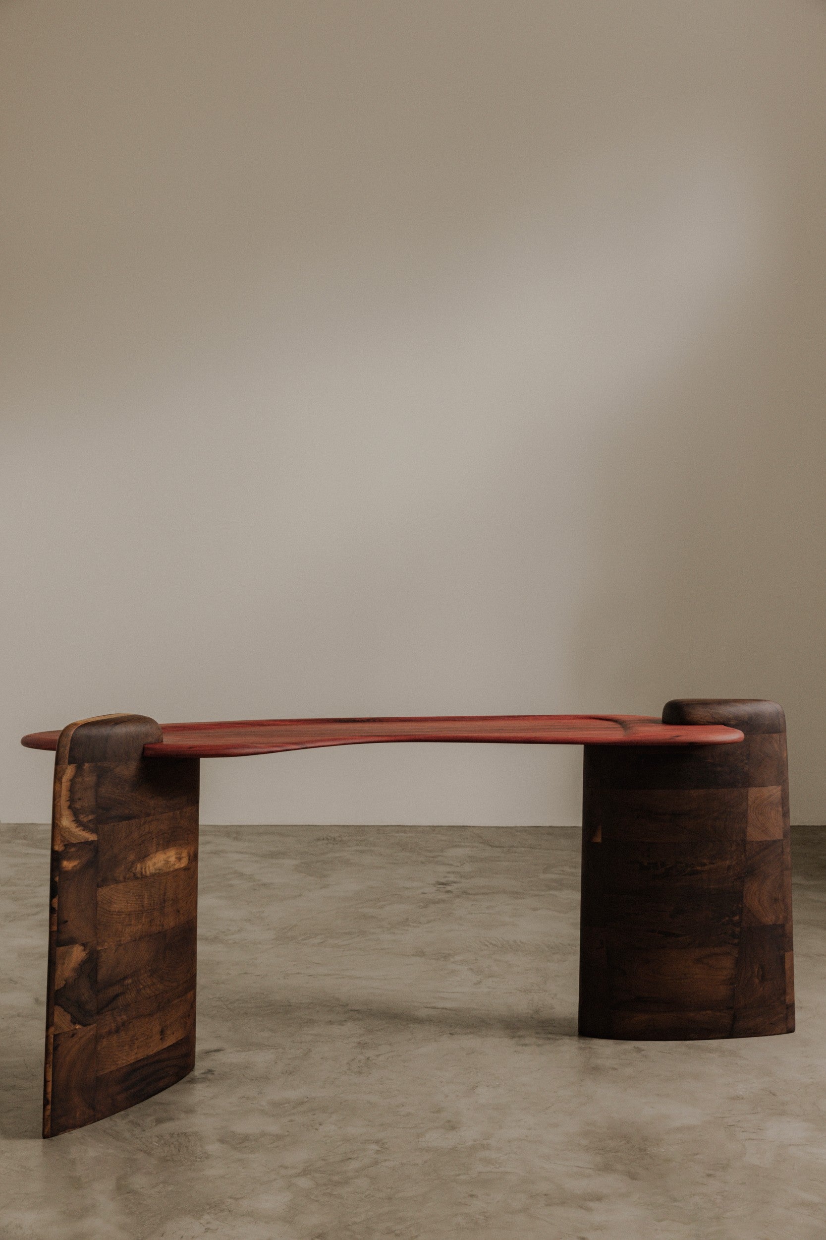 Wooden table by Estudio Prosa on neutral background with concrete floor.