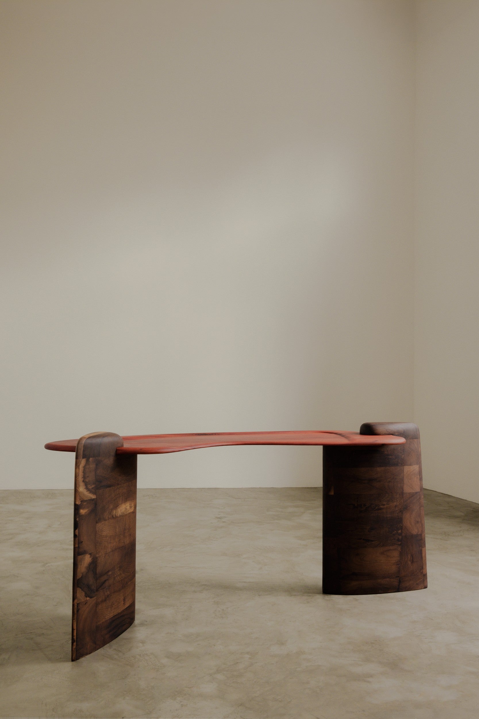 Wooden table by Estudio Prosa on neutral background with concrete floor.