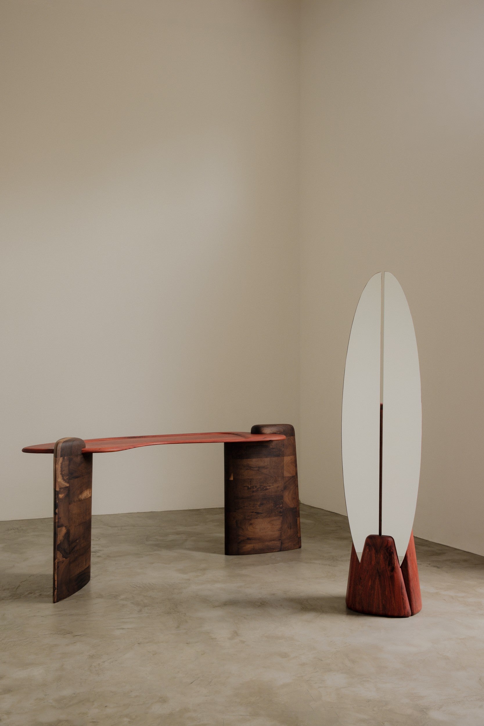 Floor standing mirror and wooden table by Estudio Prosa on a neutral background with concrete flooring.