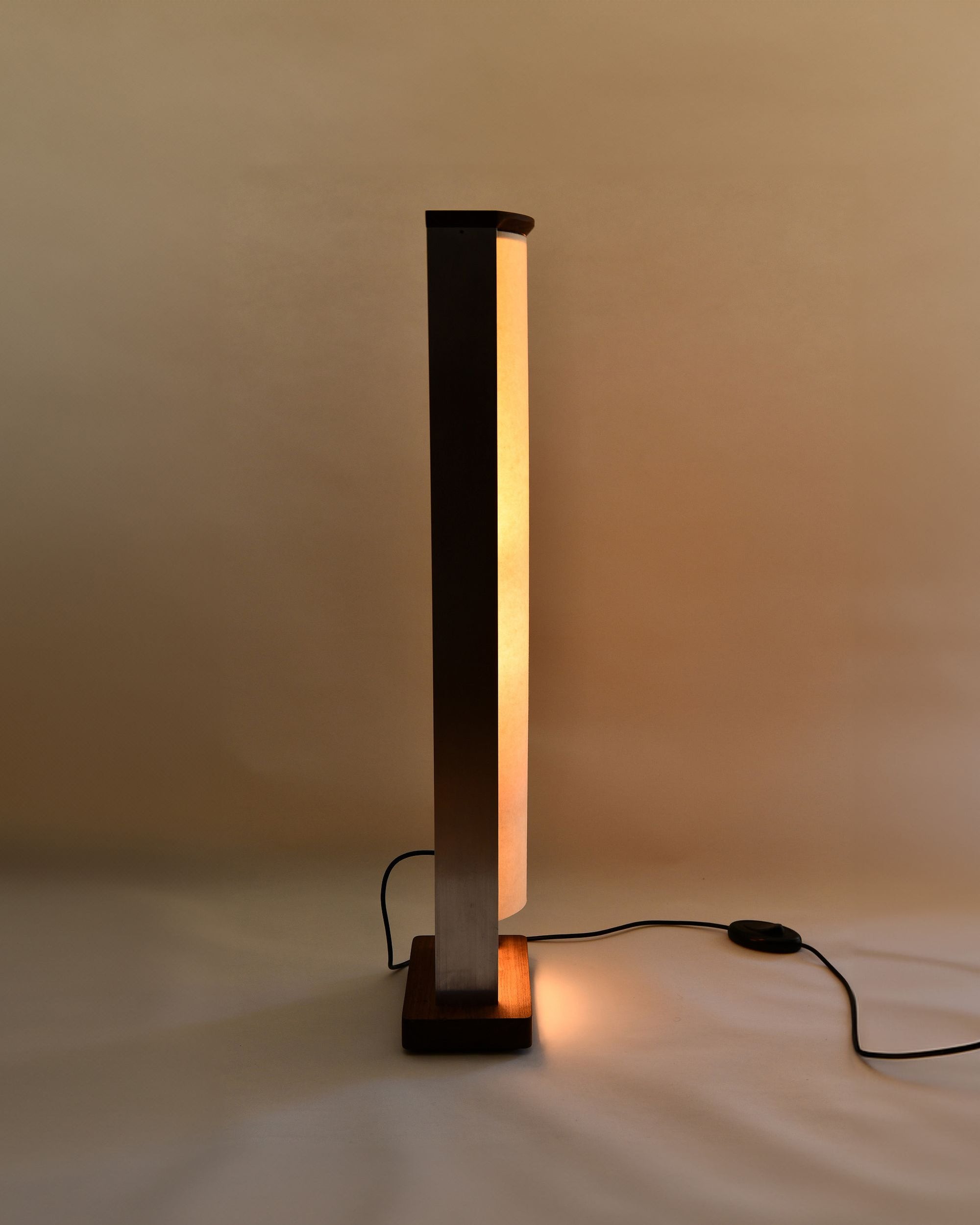 Side profile of the floor lamp by PARCTA with the light on, on a neutral background.