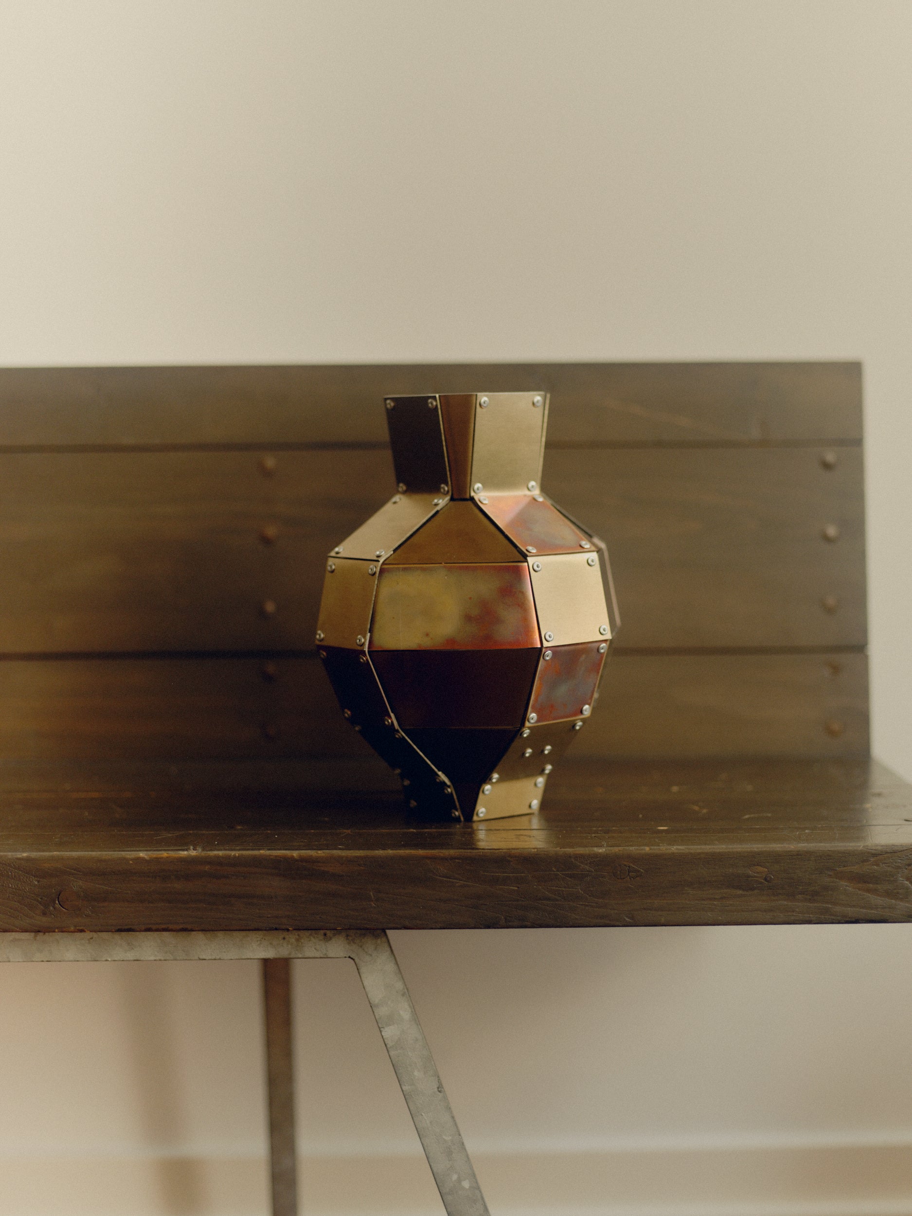 Stainless steel and copper decorative object by Theo Galliakis sat on wooden bench.