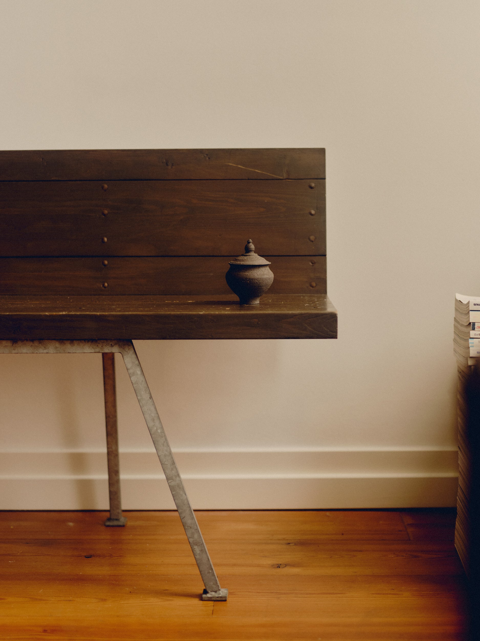 Small textured ceramic jar with a lid by Bastian Bjerge sat on a wooden bench.