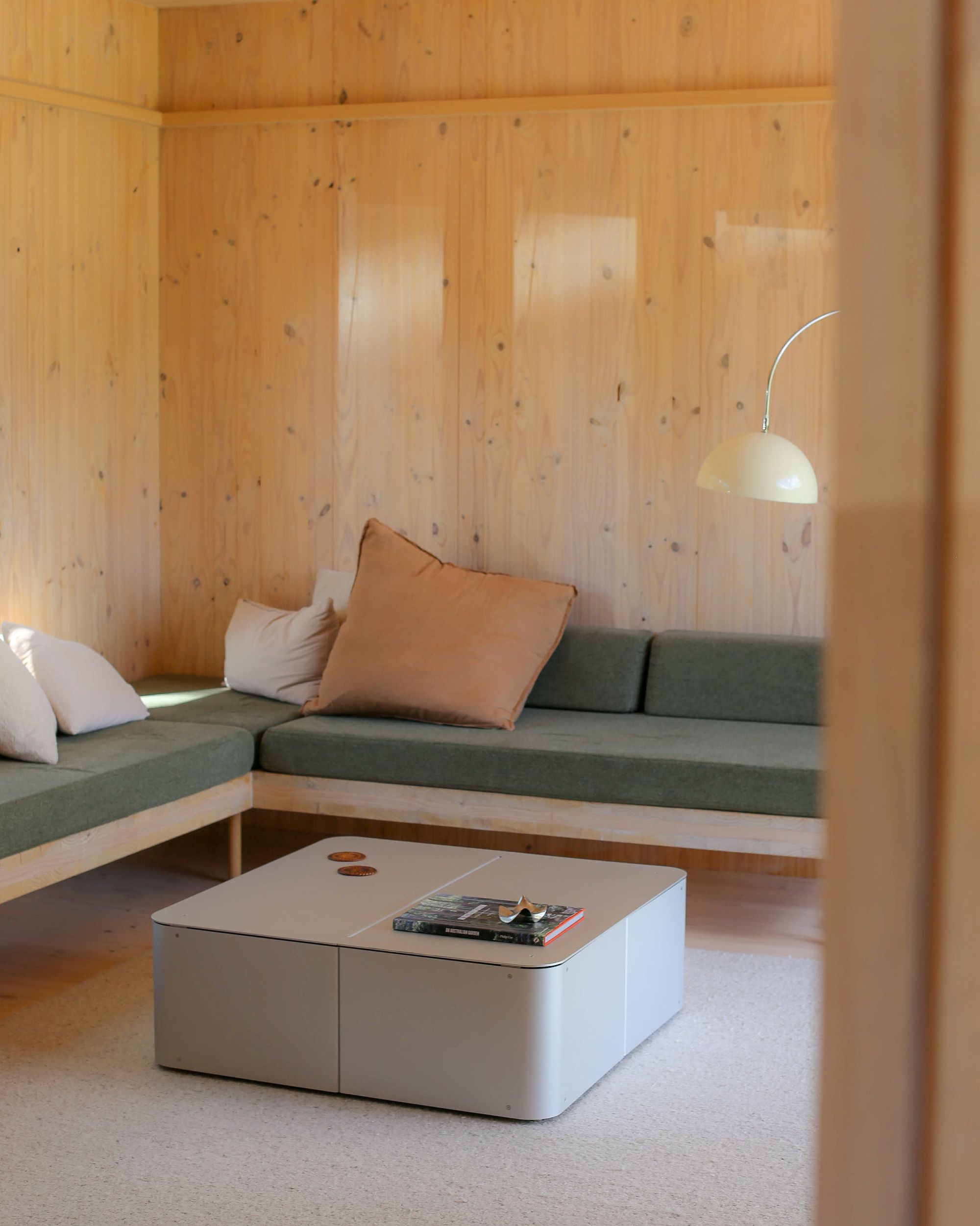 Coffee Table by PARCTA in a living area in a wood cabin on a neutral rug with a green sofa.