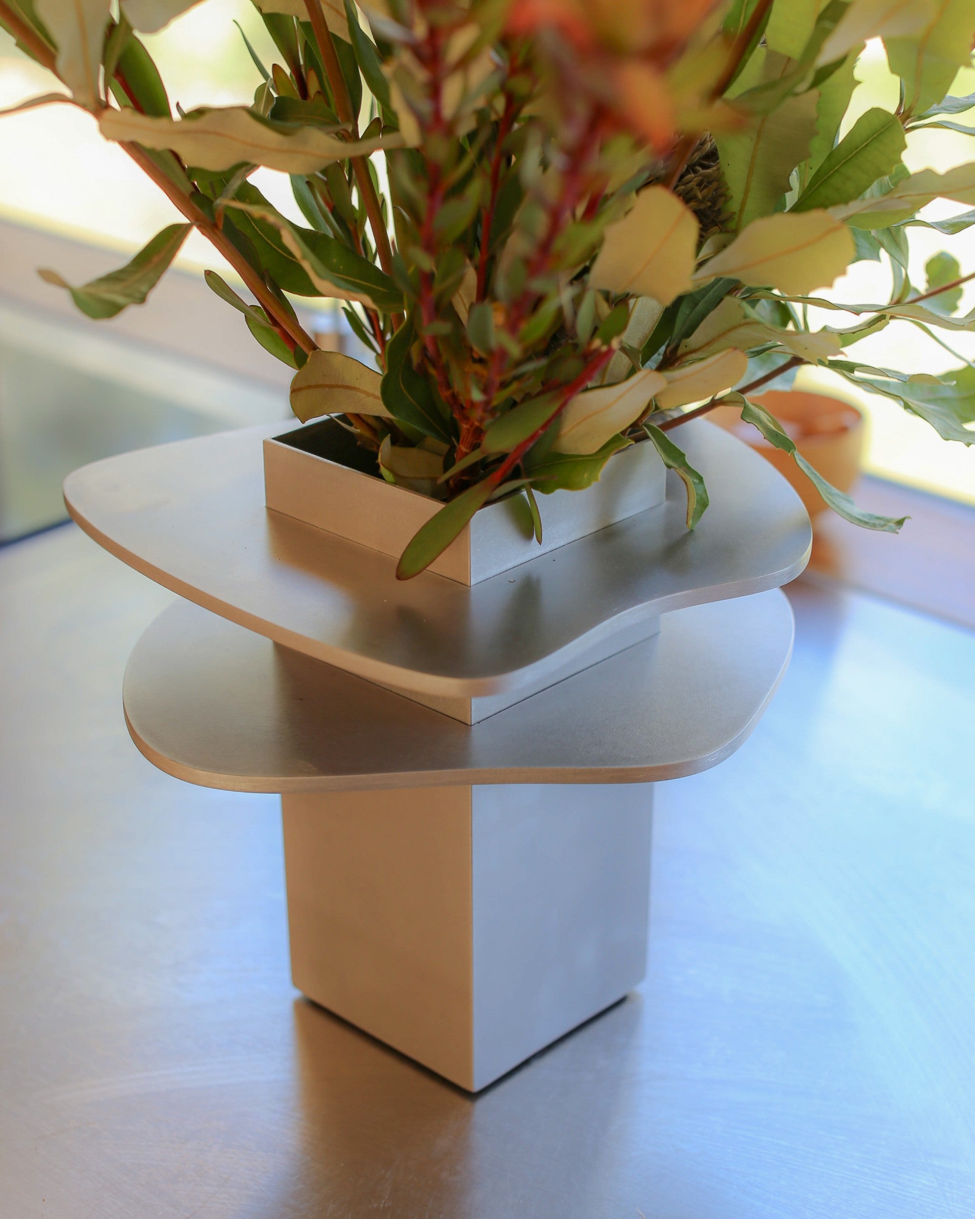 Vase by PARCTA with decorative arrangement of  flowers on a wooden table.