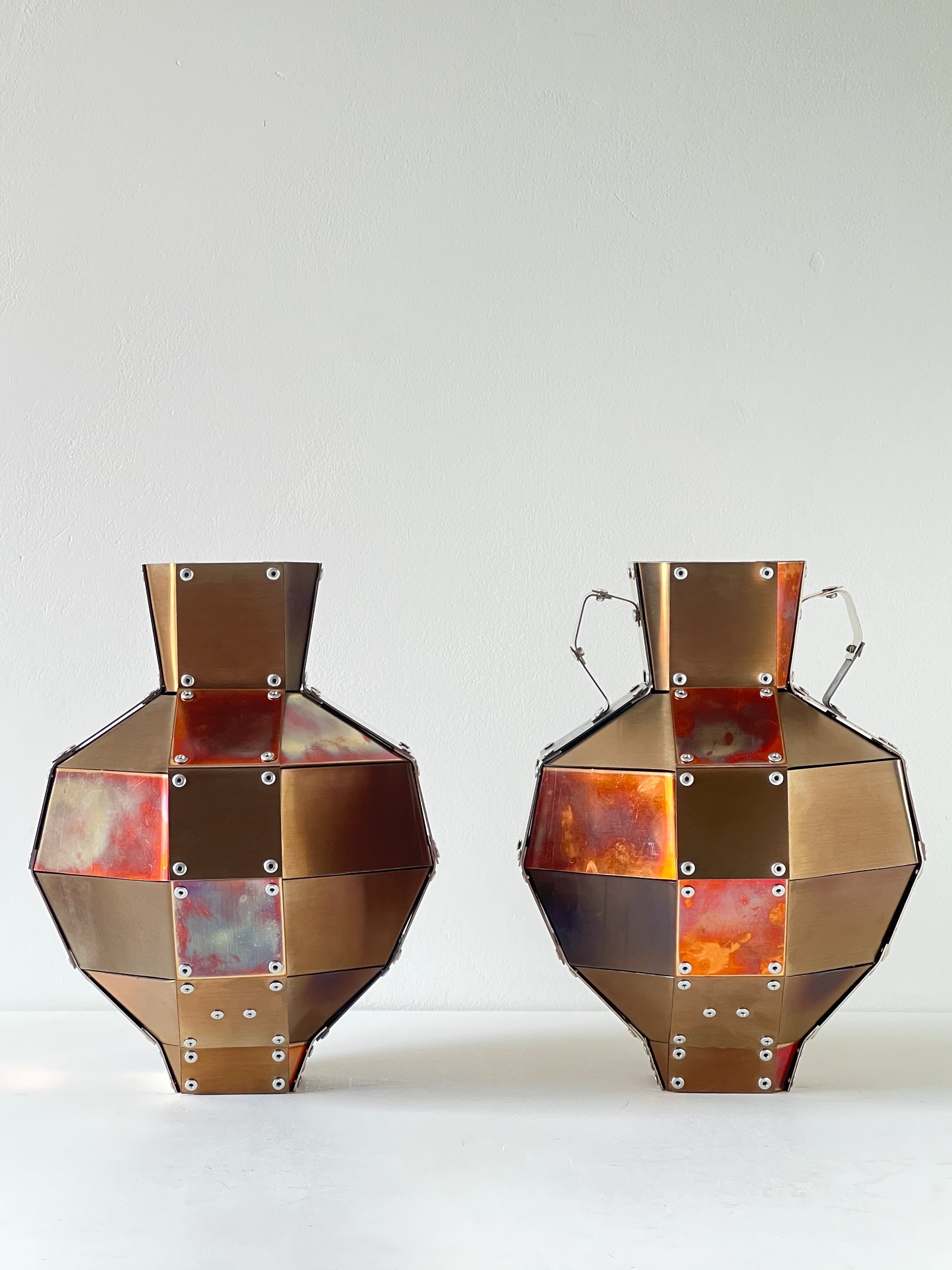 Two stainless steel and copper decorative objects by Theo Galliakis on a white background.