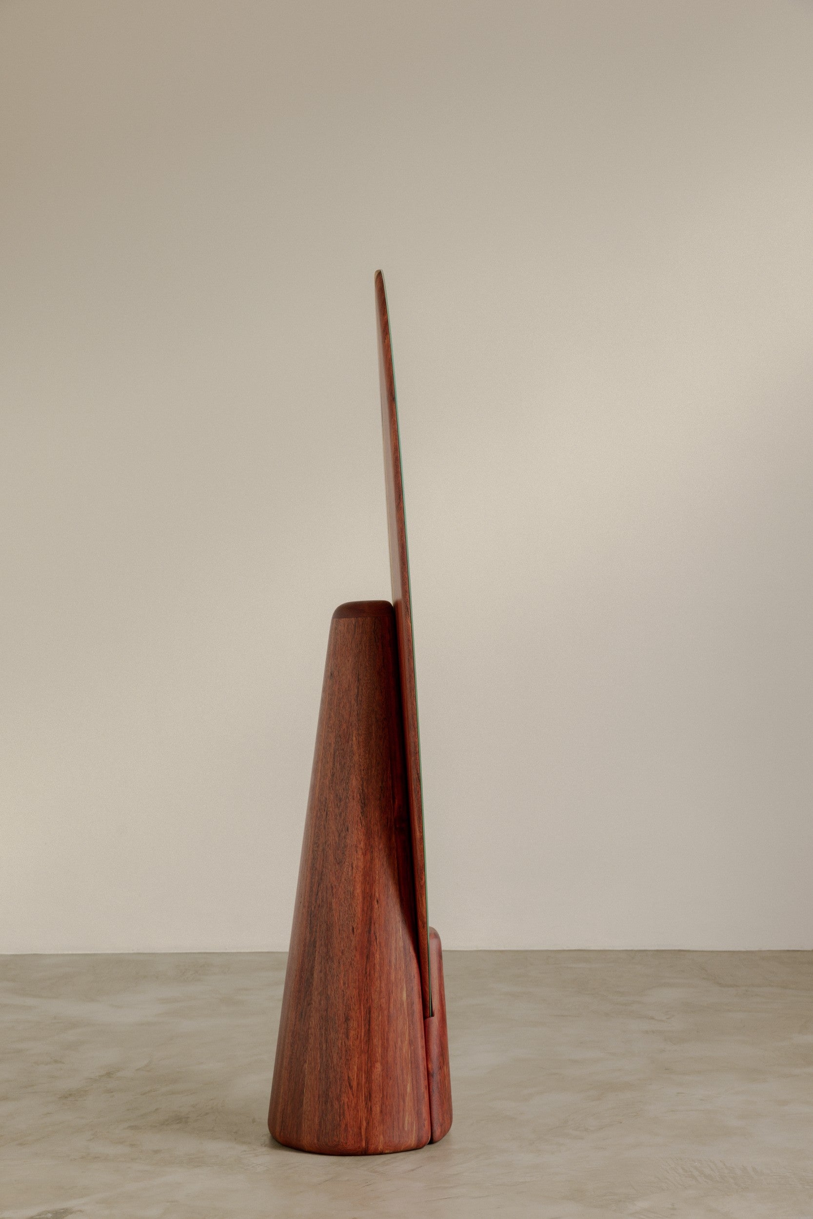 The side of a floor standing mirror by Estudio Prosa on a neutral background with concrete flooring.