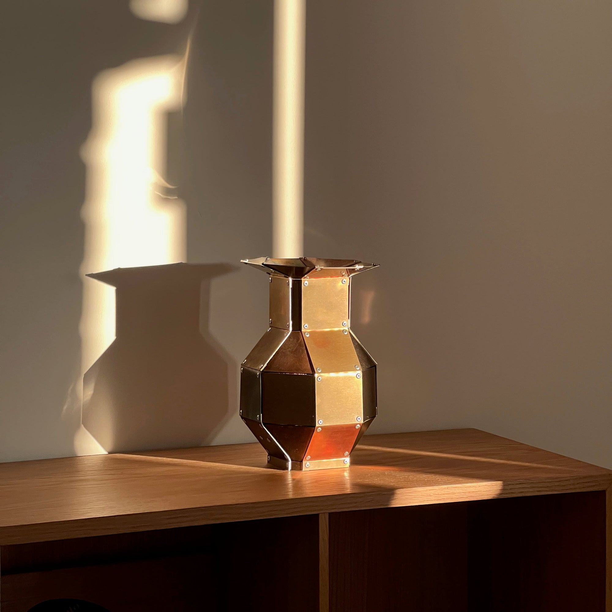 Stainless steel and copper decorative object by Theo Galliakis sat on a wooden cabinet.