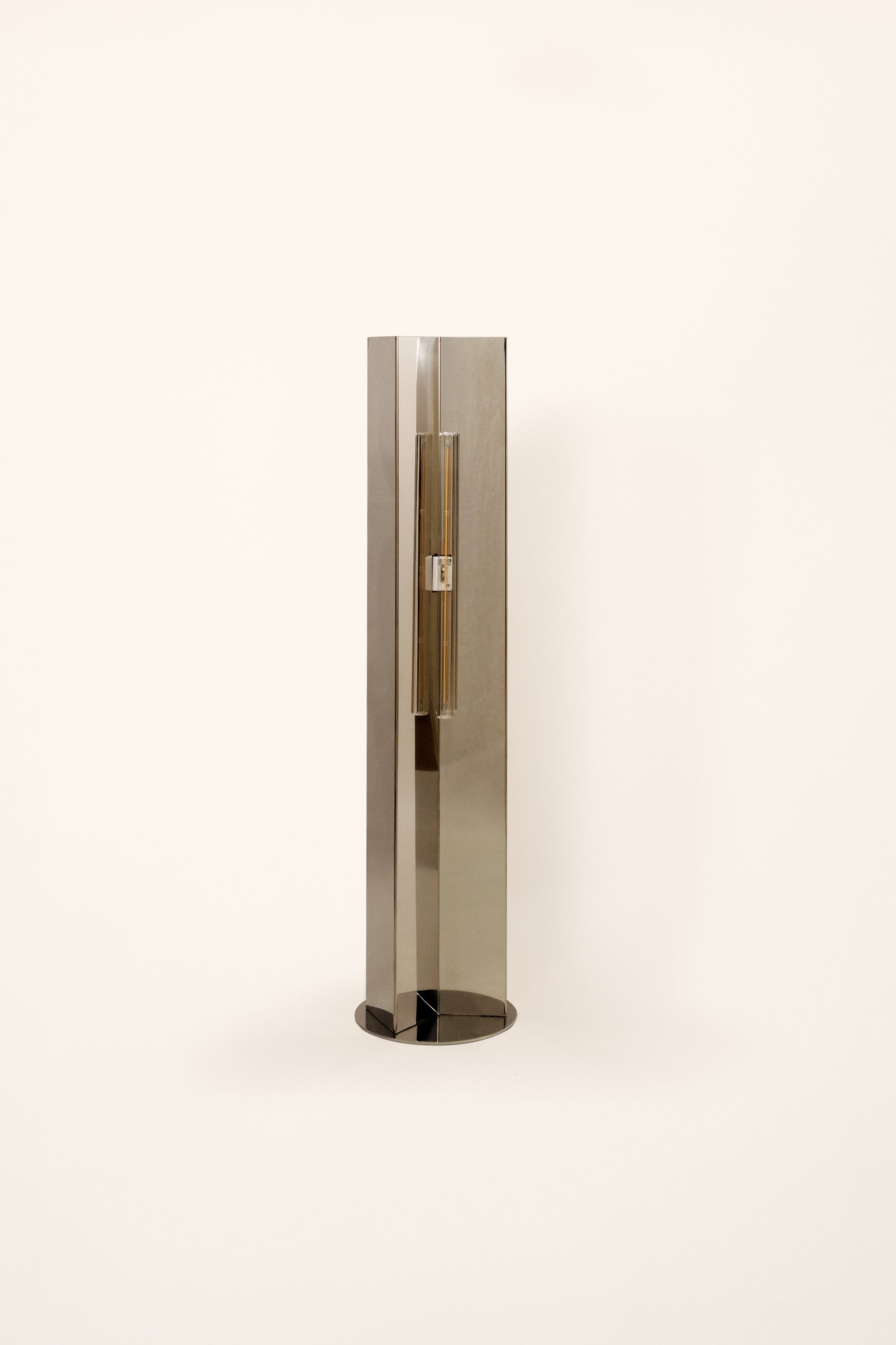Polished steel foot lamp by Violaine d'Harcourt on a white background with light off.