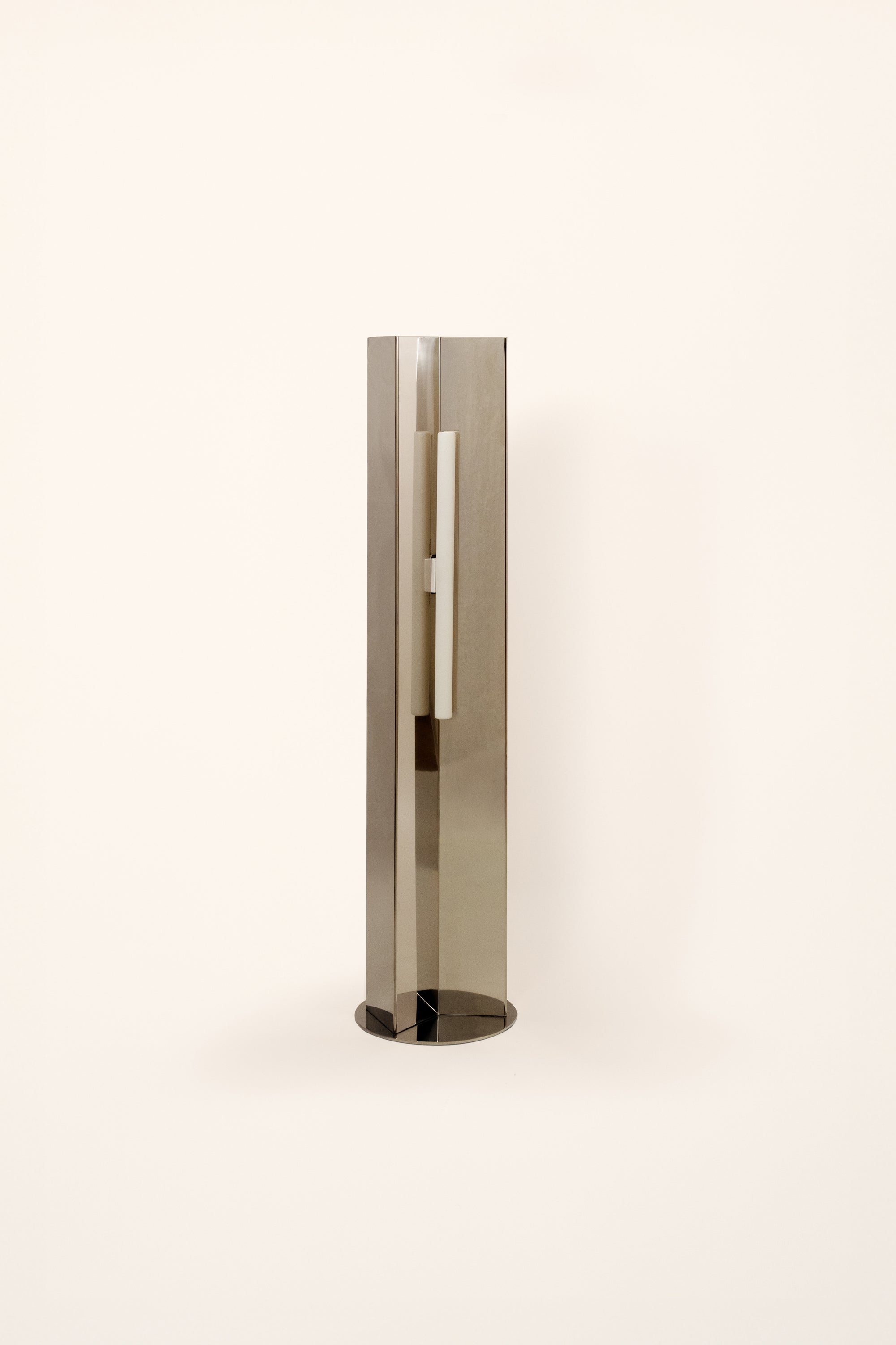 Polished steel foot lamp by Violaine d'Harcourt on a white background with light off.