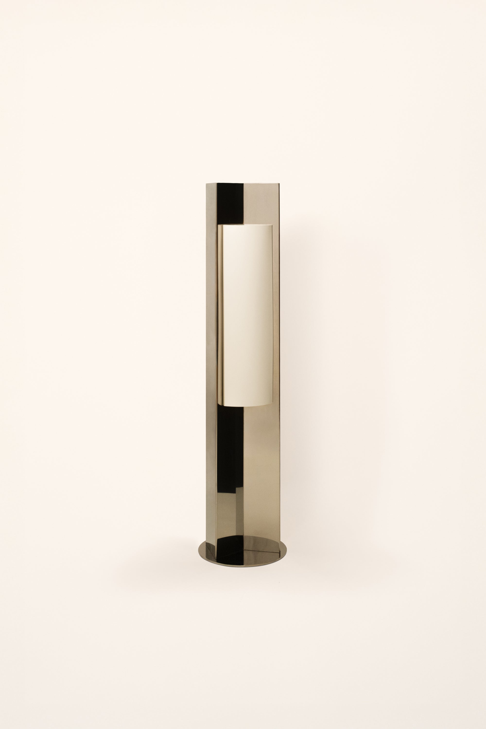 Polished steel foot lamp with paper diffuser by Violaine d'Harcourt on a white background with light off.