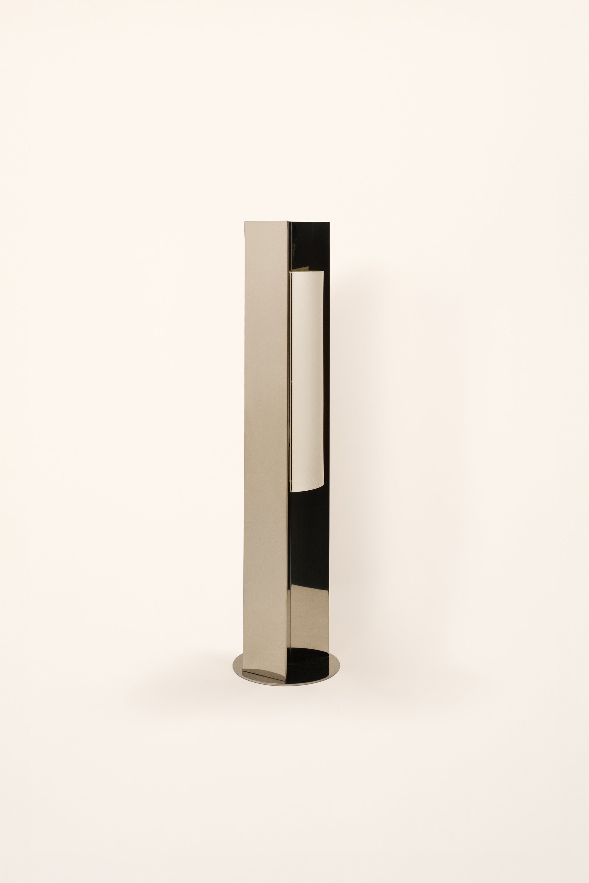 Polished steel foot lamp by Violaine d'Harcourt with paper diffuser on a white background with light off.