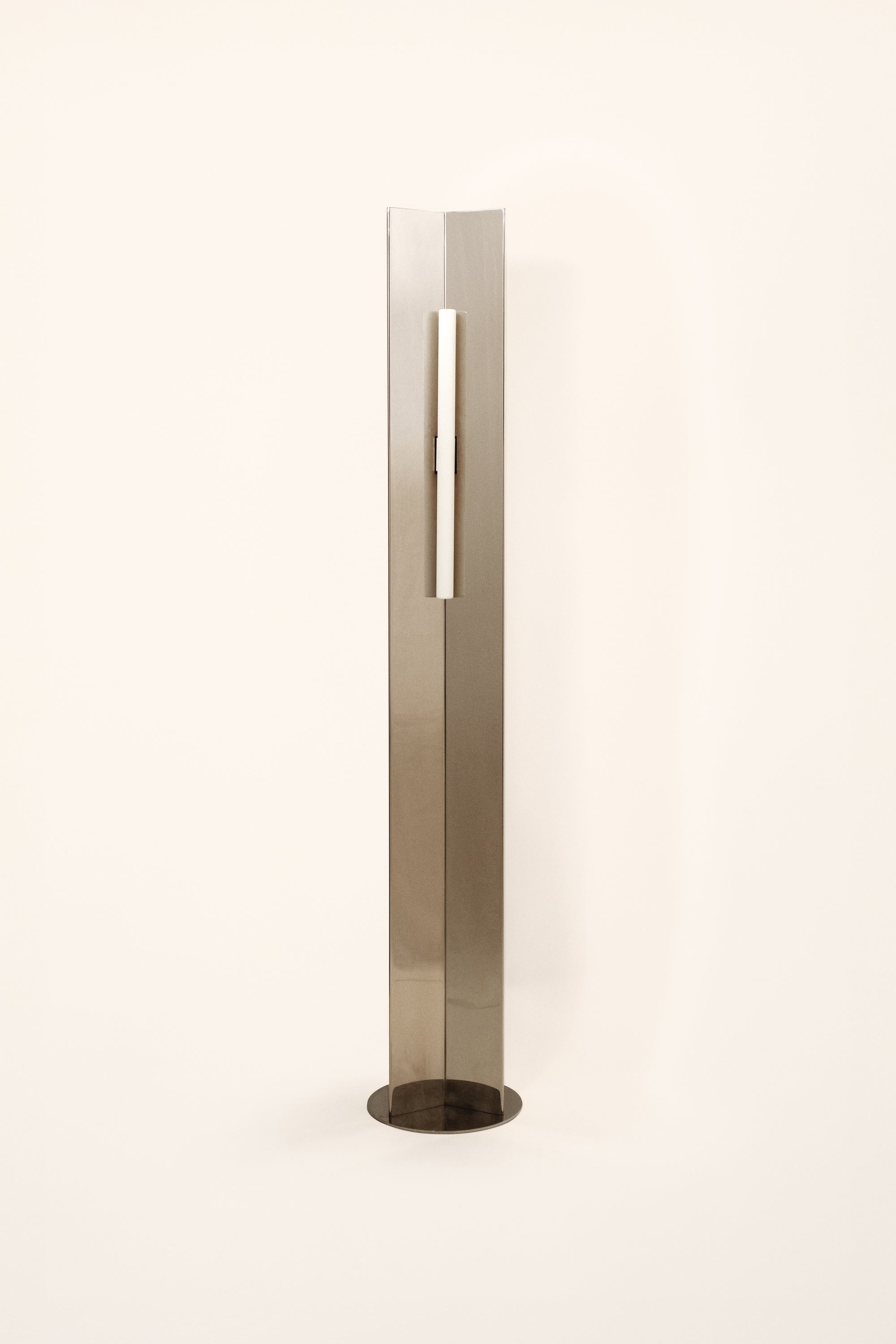 Polished steel foot lamp by Violaine d'Harcourt on a white background with light off.