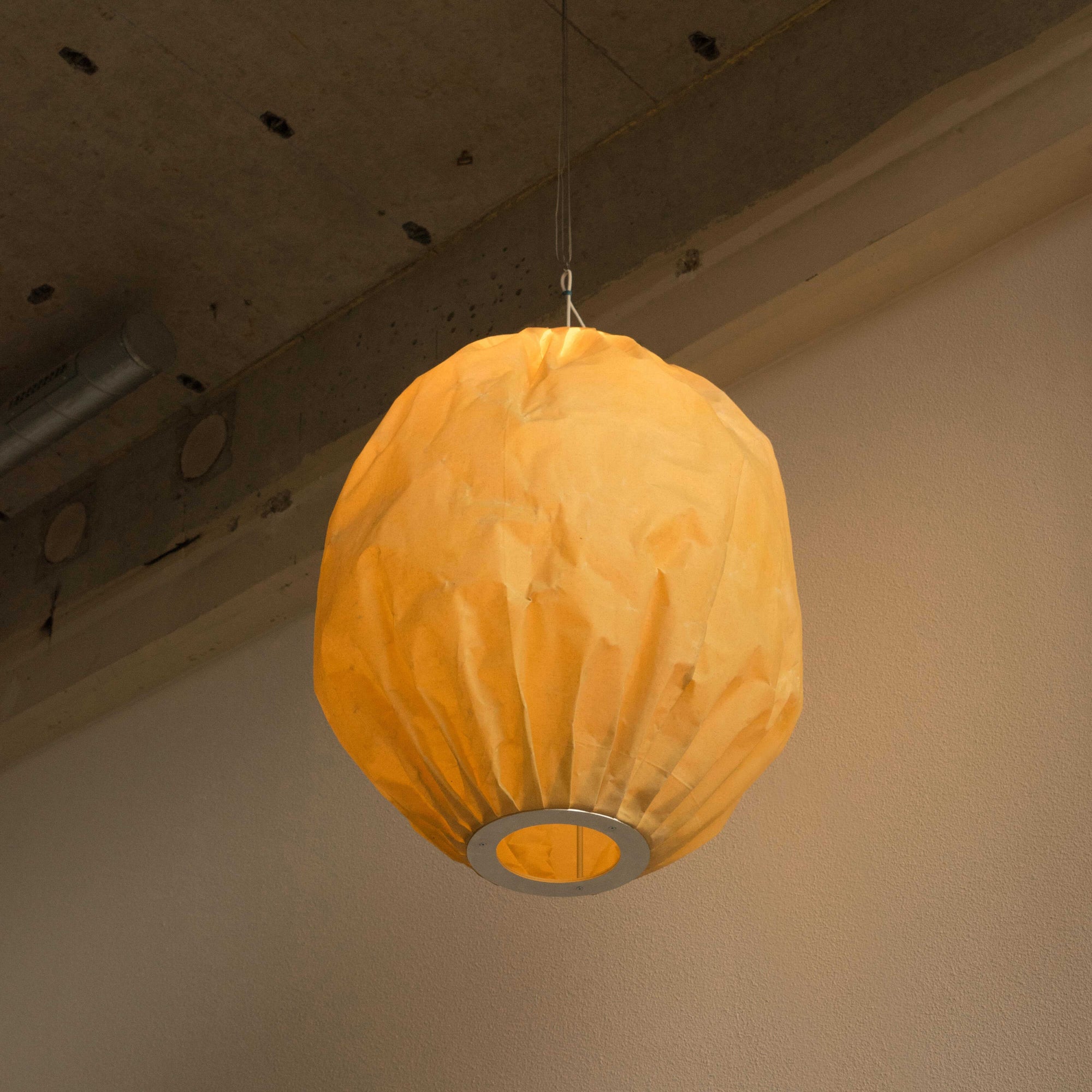 Beeswax Bubble pendant light by Pablo Bolumar hanging from the industrial ceiling.