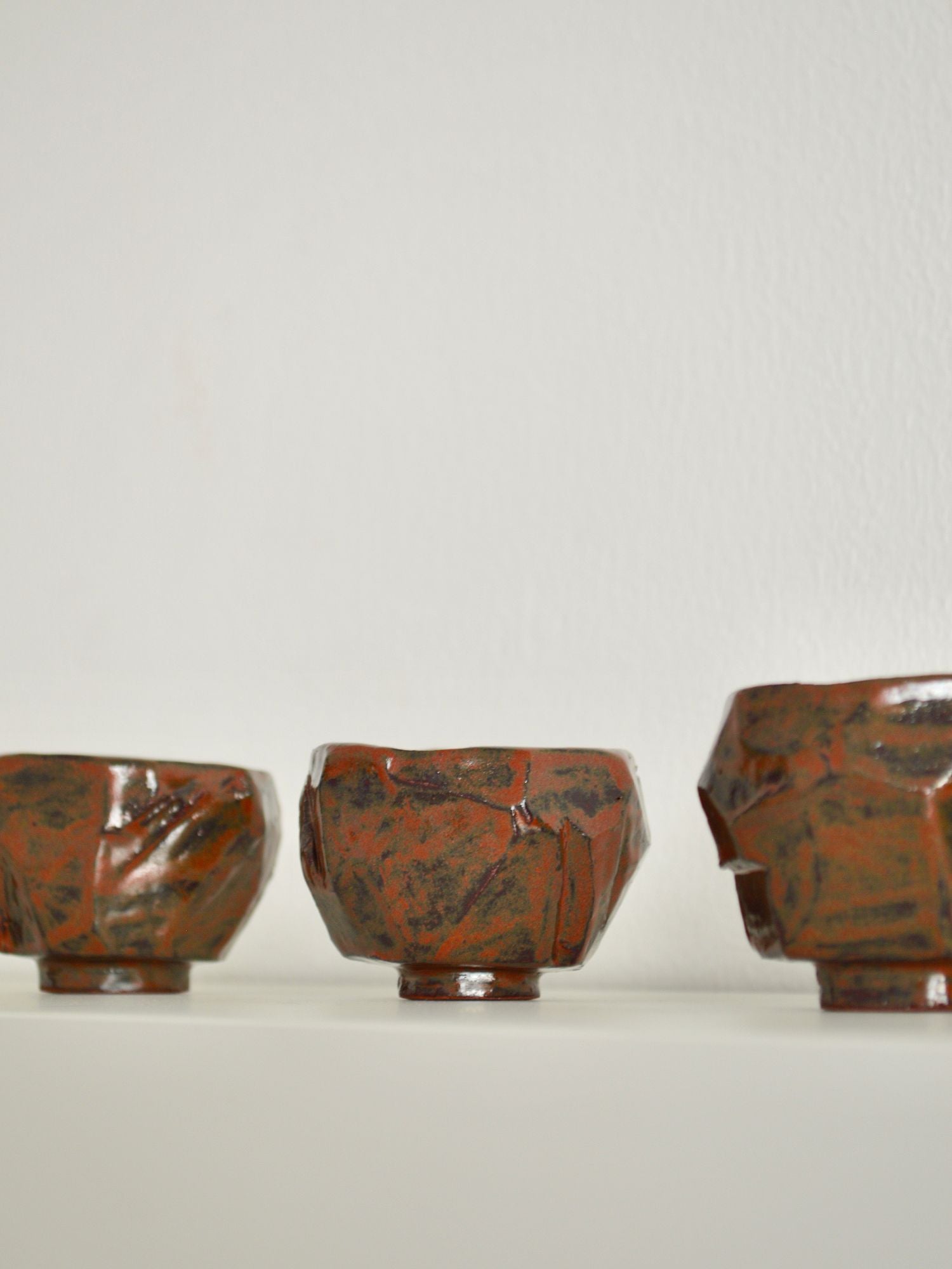 Three ruby coloured coffee cups by Zeynep Boyan sat besides each other on a neutral background.