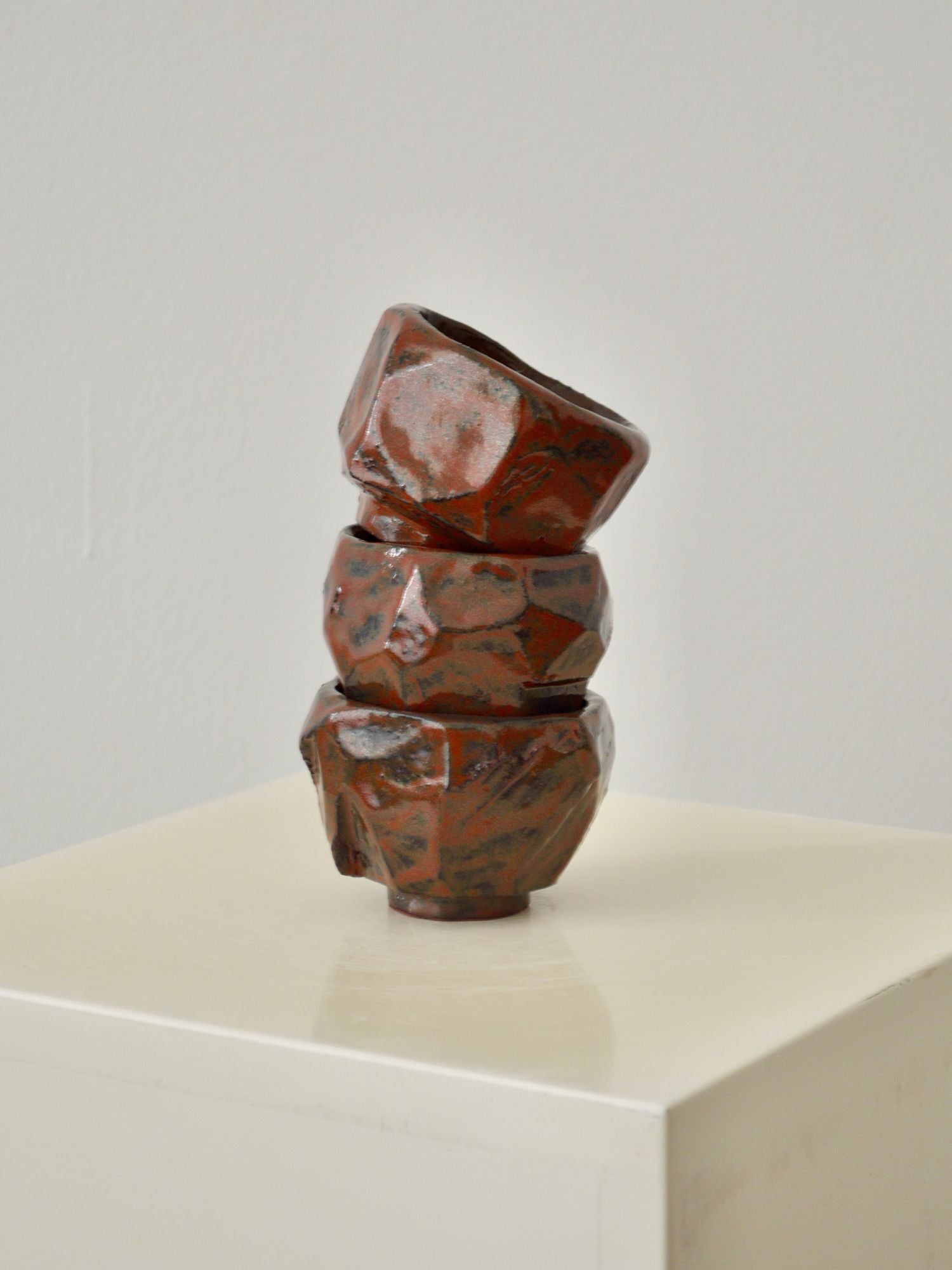 A stack of three ruby coloured coffee cups by Zeynep Boyan on a neutral background.