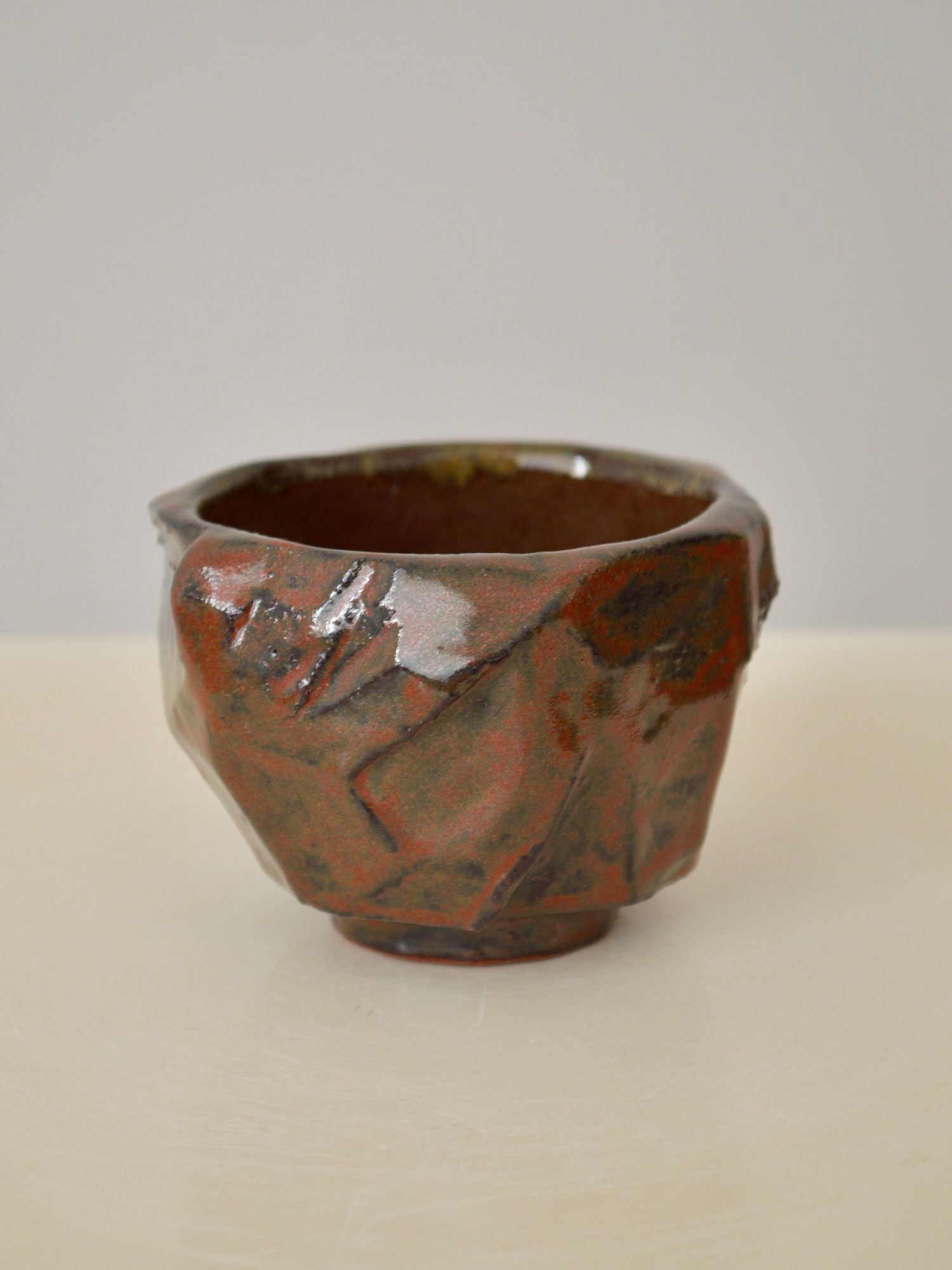 A ruby coloured coffee cup by Zeynep Boyan on a neutral background.