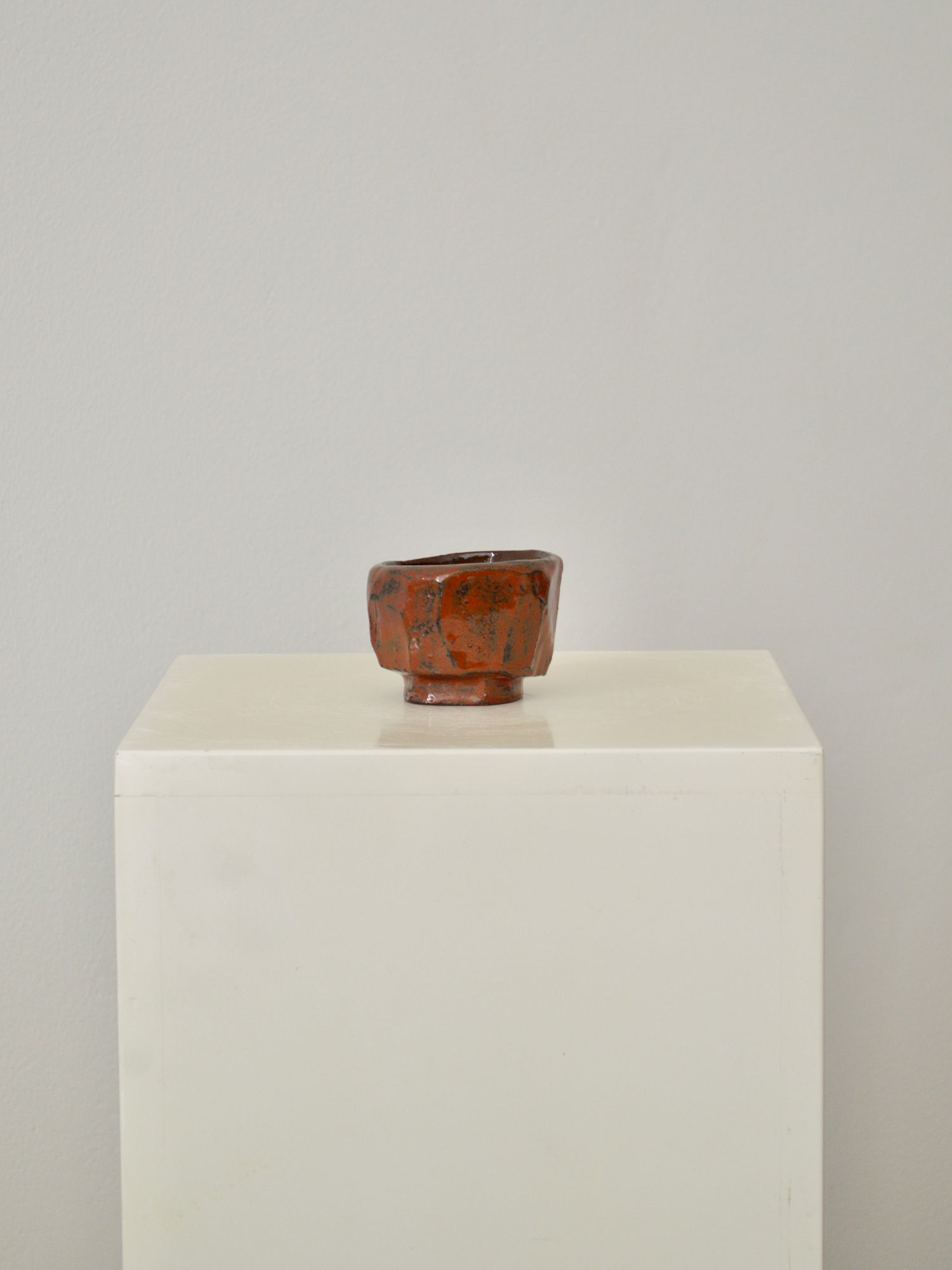 A ruby coloured coffee cup by Zeynep Boyan on a white plinth with a neutral background.
