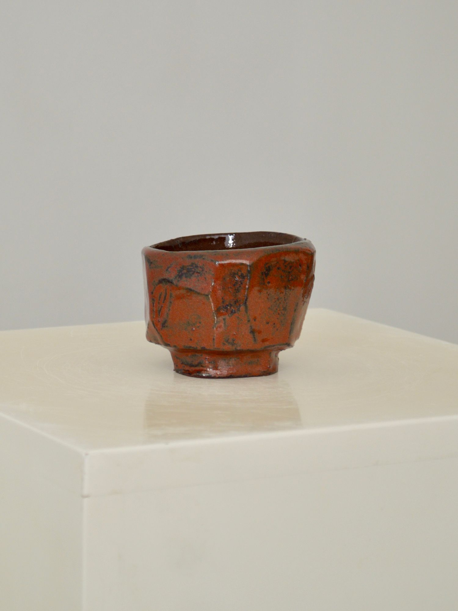 A ruby coloured coffee cup by Zeynep Boyan on a neutral background.