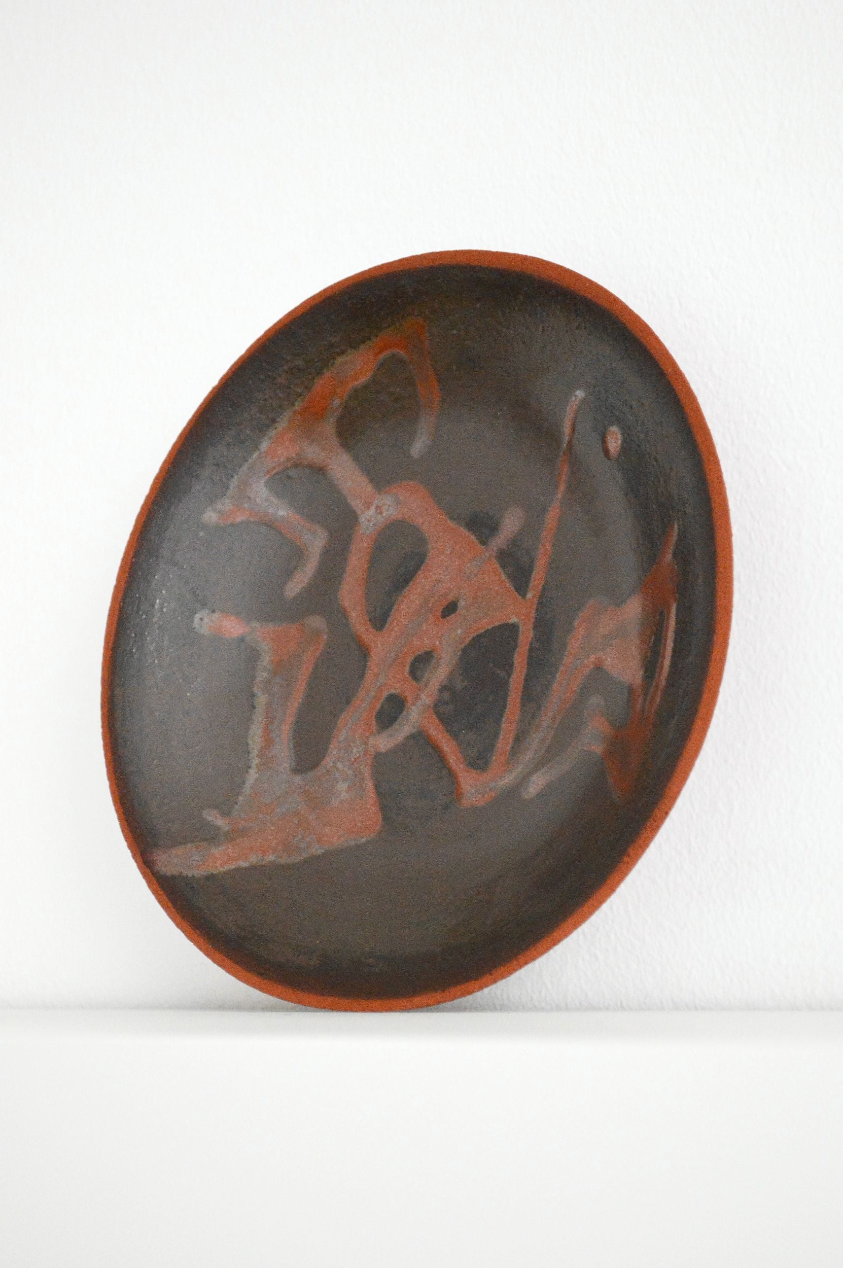 A decorative ceramic plate with an organic swirling pattern in shades of brown by Zeynep Boyan on a white background.