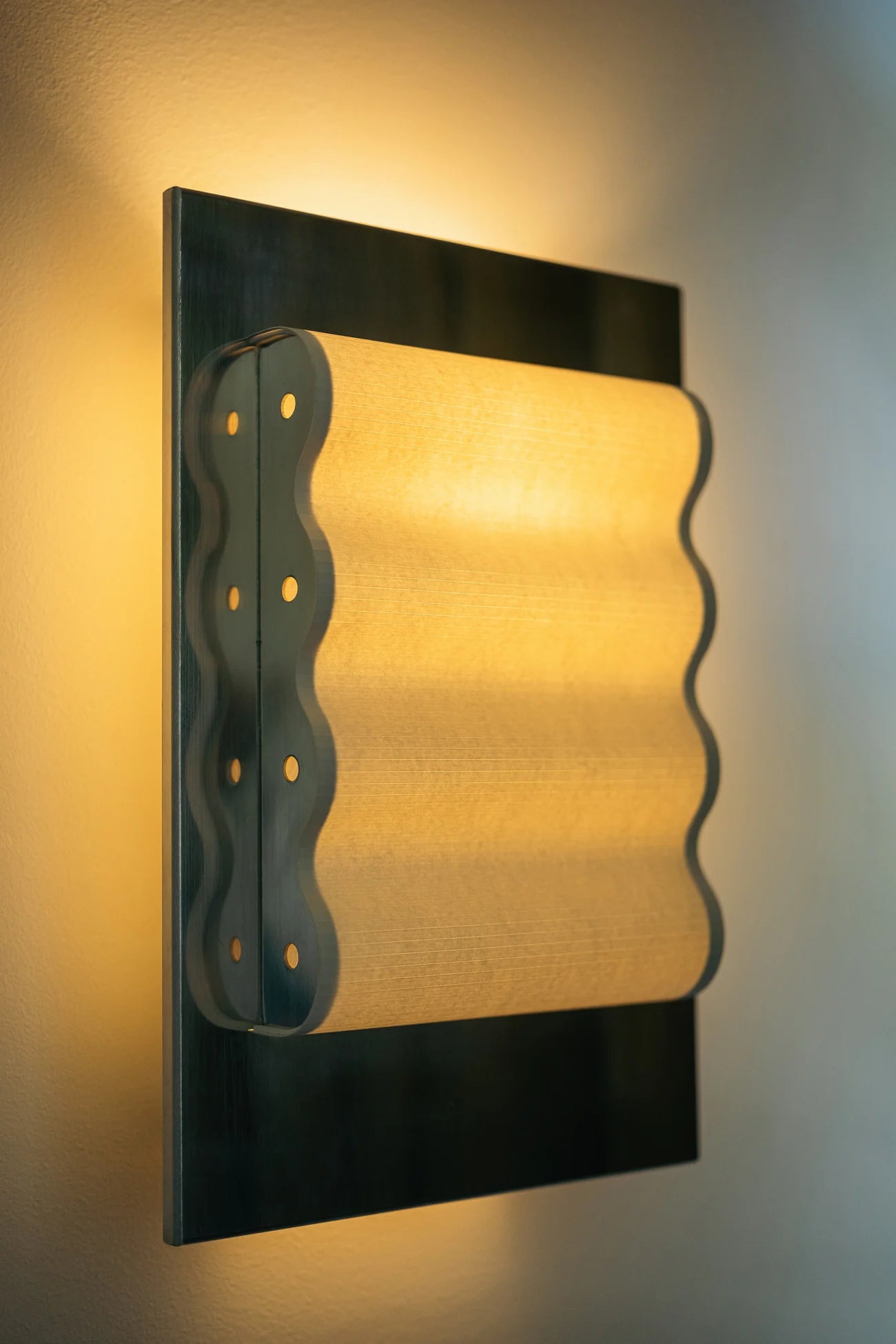 Framed wall light fixture in polished stainless steel with a paper shade by Violaine d'Harcourt on a beige wall with light off.
