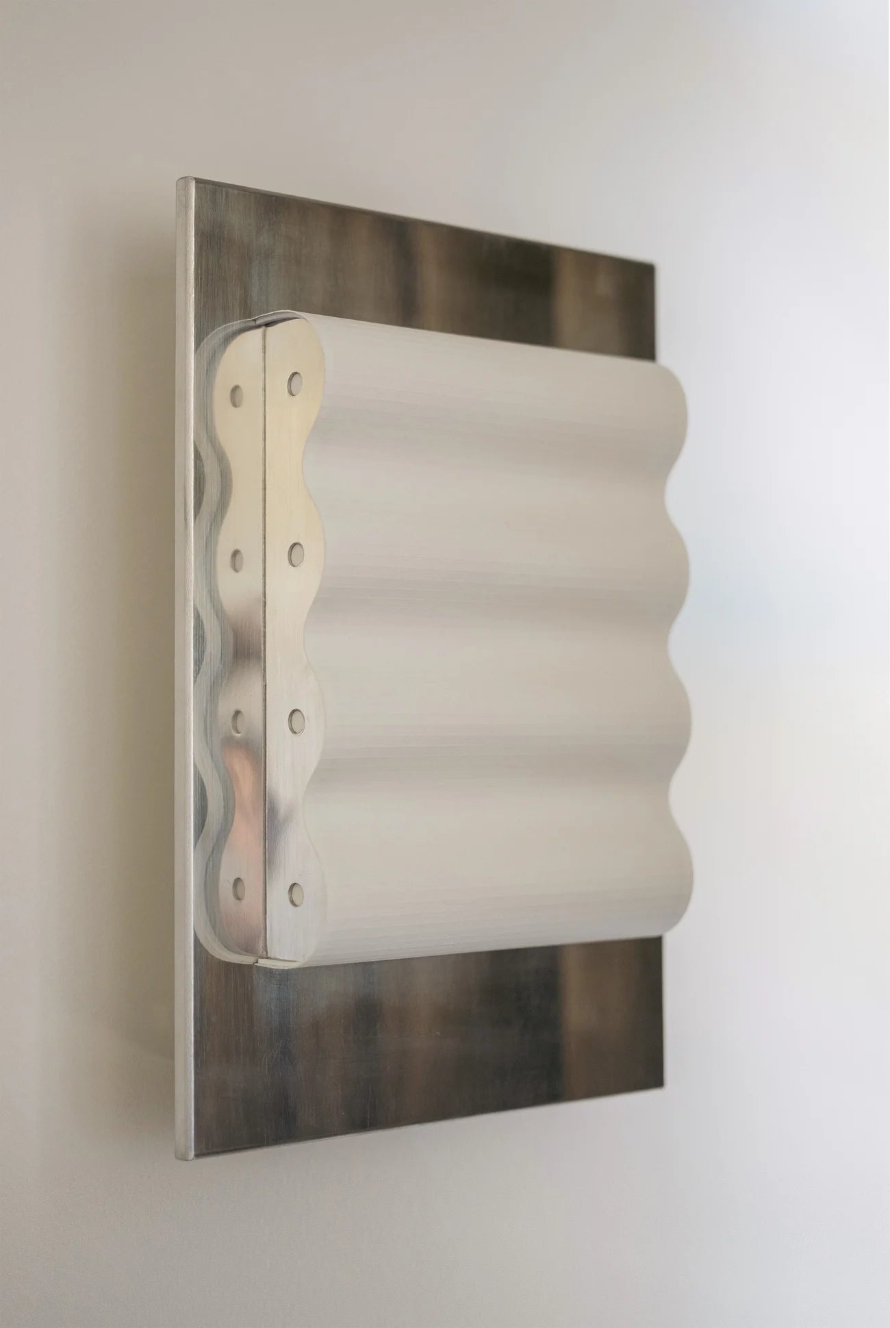 Framed wall light fixture in polished stainless steel with a paper shade by Violaine d'Harcourt on a beige wall with light off.