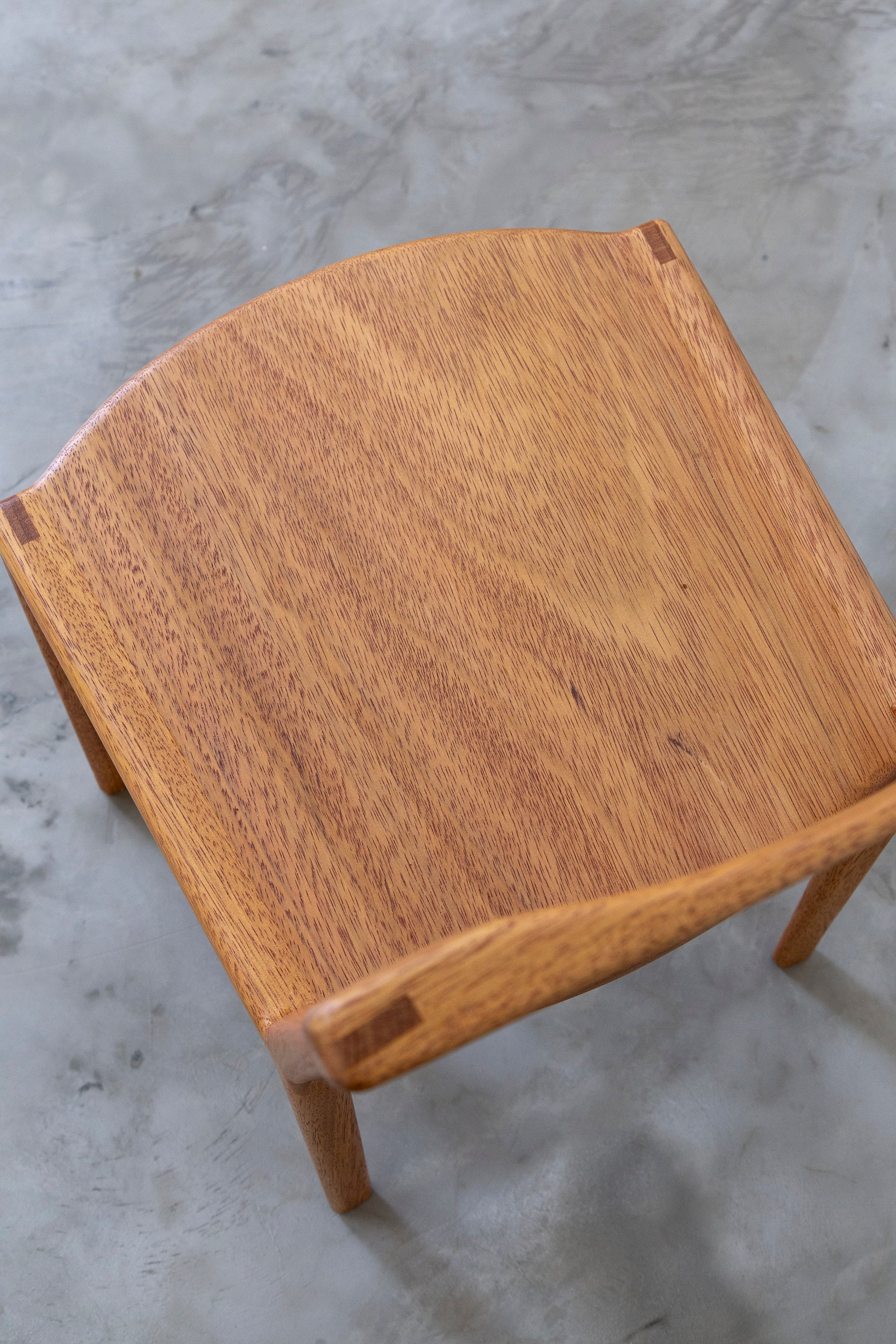Top view of wooden chair by Estudio Prosa with on a grey concrete floor.