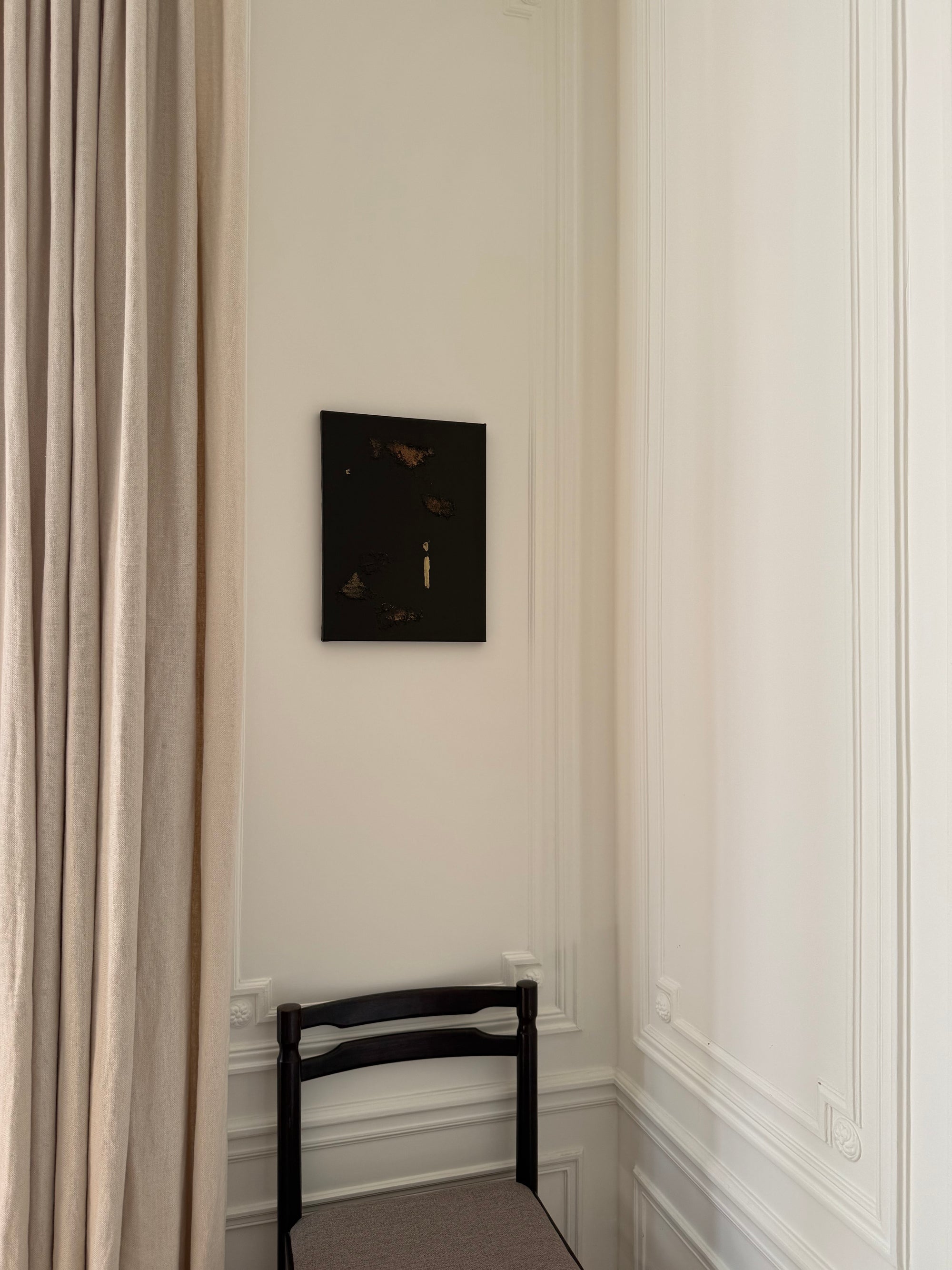 Gold and brown decorative abstract wall by Noelia Hobeika displayed on a decorative wall with a beige curtain alongside it, positioned above a chair. 