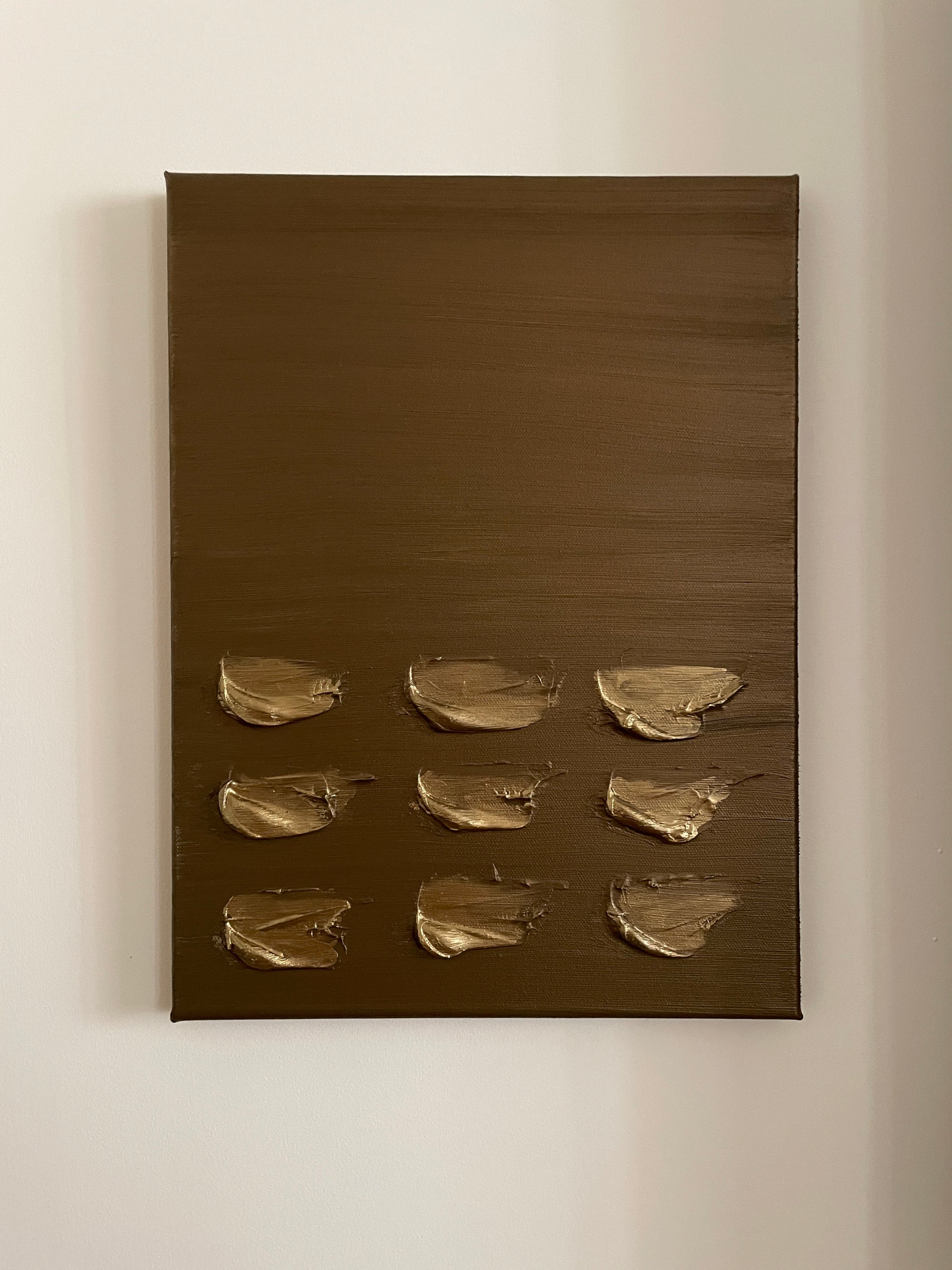 Gold and brown abstract wall art by Noelia Hobeika on a white wall.