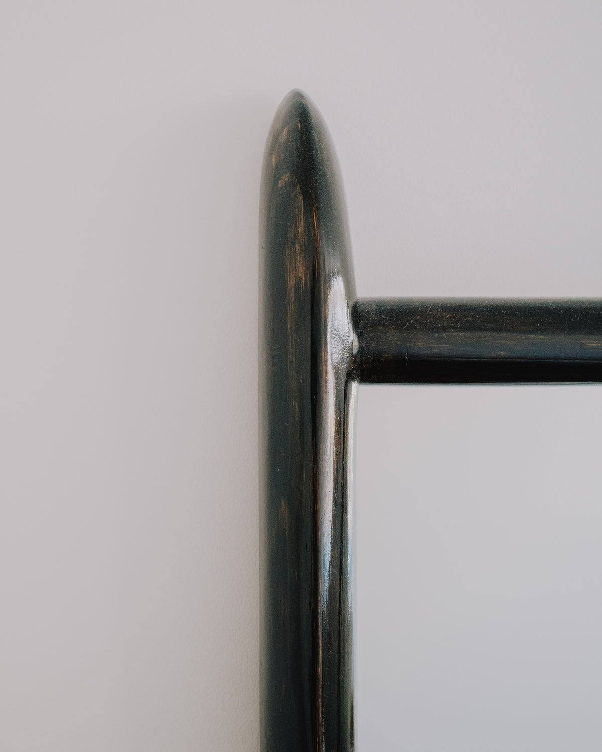 Close up of Glade mirror by Calum Stevens hanging on a neutral wall.