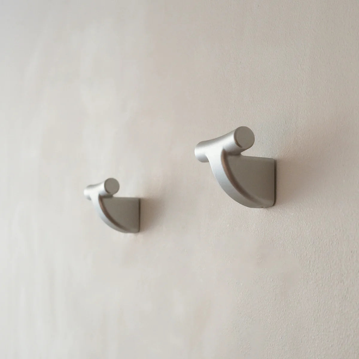 Two silver mooring hooks by PARCTA mounted on a neutral wall.