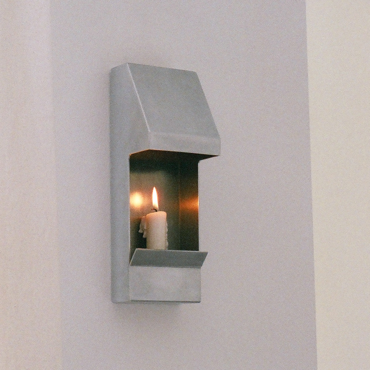 Candle holder by PARCTA with a lit candle inside on a neutral background.