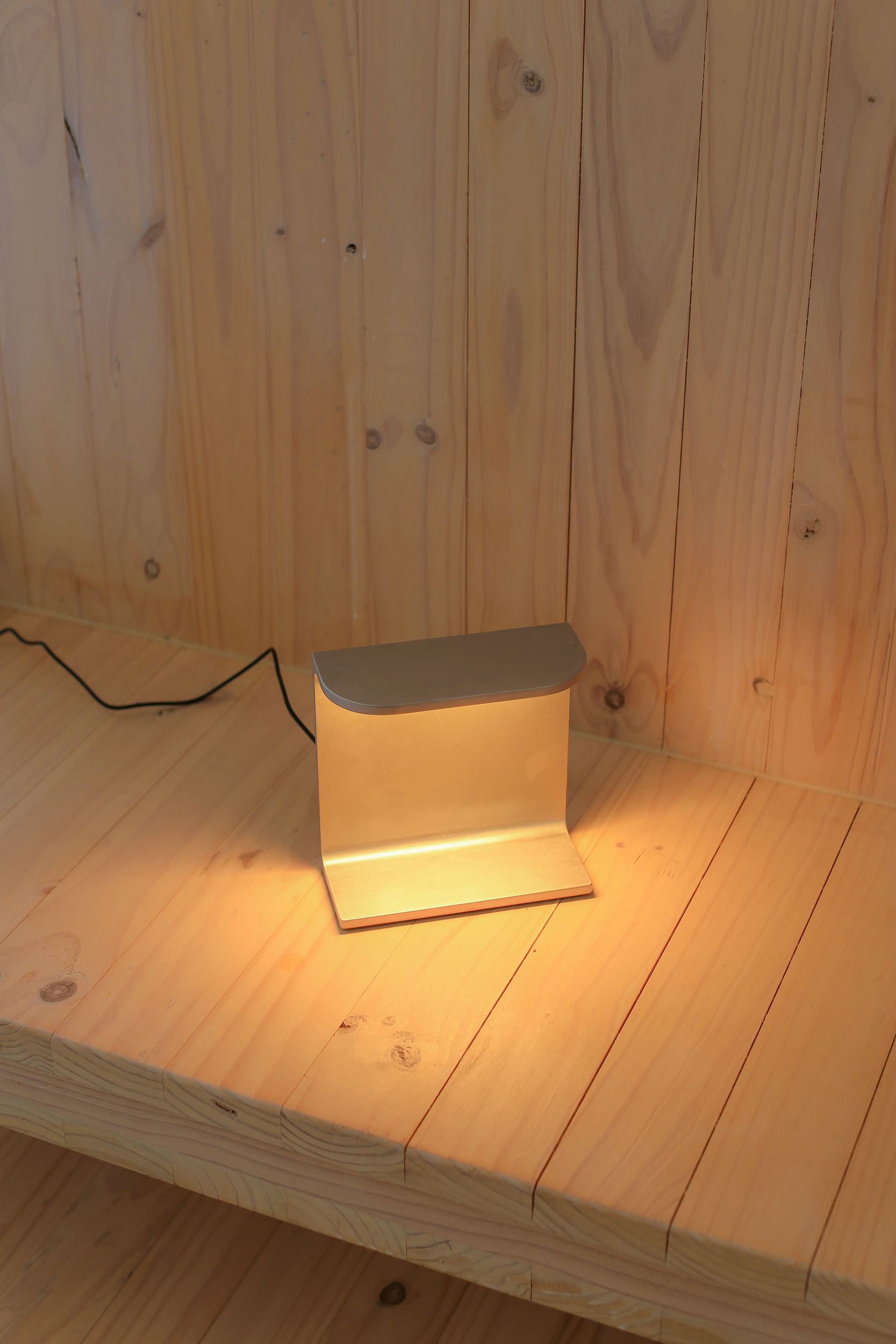 Desk lamp by PARCTA with the light on sat on a wooden background.