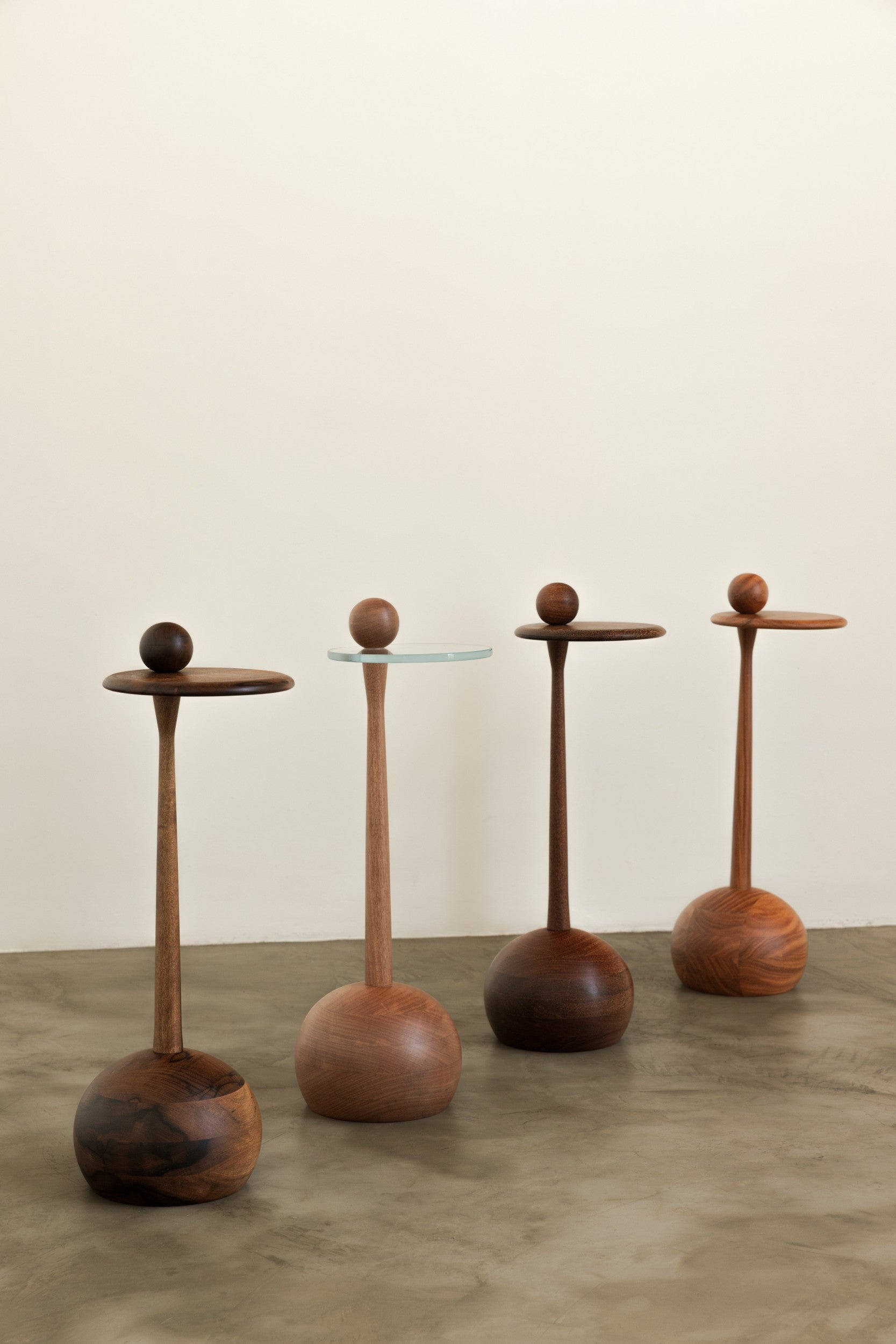 Set of four wooden side tables on a neutral background by Estudio Prosa.