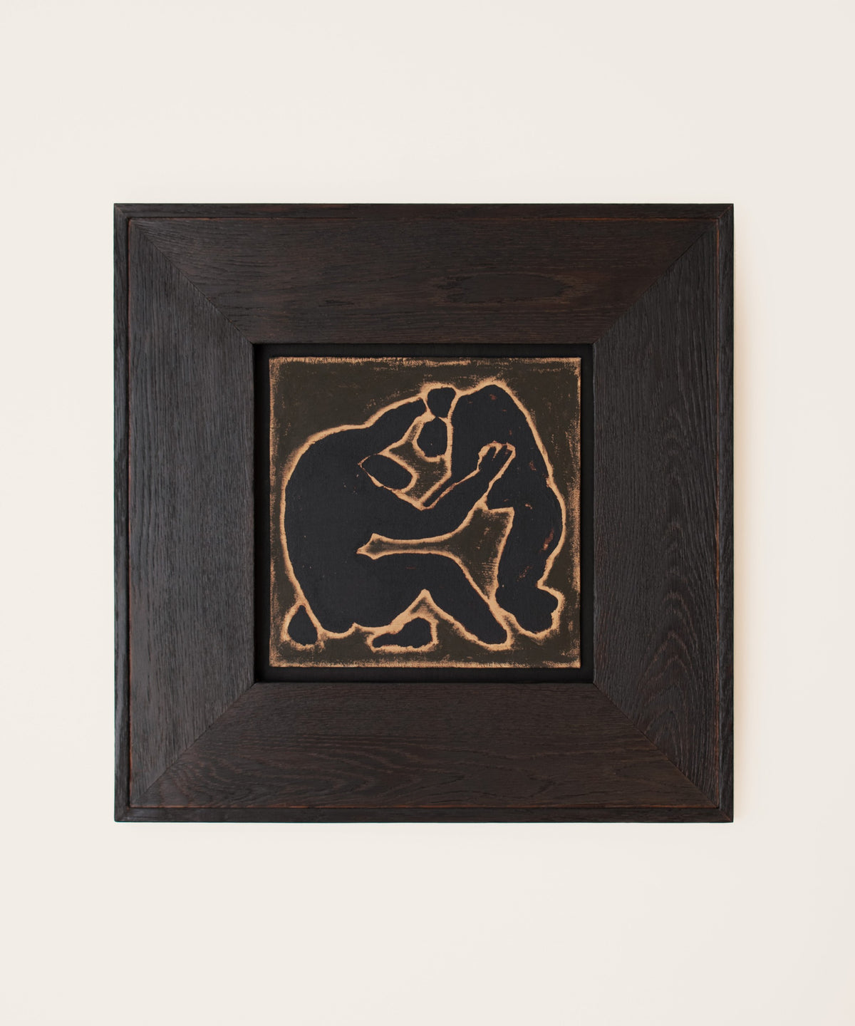 Original wall art by Marcsen featuring a dark silhouette of two embracing figures on a earthy background, set within a thick dark brown wooden frame against a light cream wall.