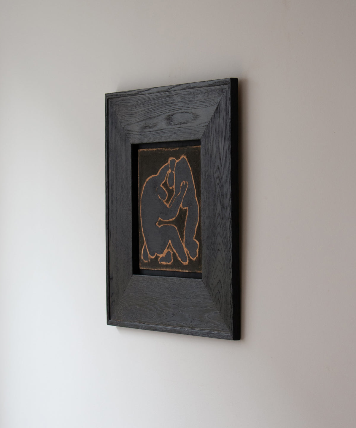 Original wall art by Marcsen featuring a dark silhouette of two embracing figures on a earthy background, set within a thick dark brown wooden frame against a light cream wall.