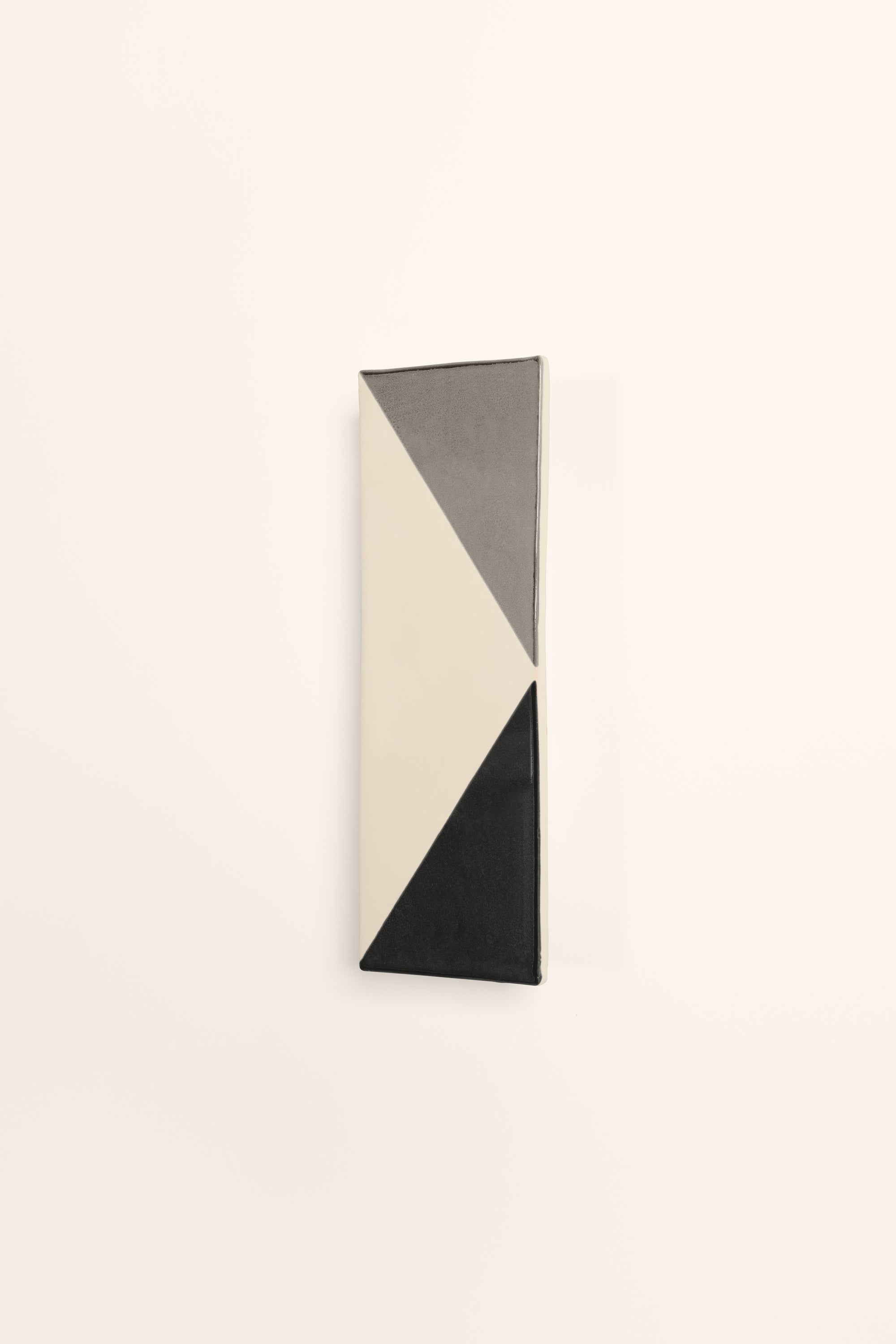 Wall-mounted light fixture by Violaine d'Harcourt with the light off. The design is a geometric pattern in grey, black and white.