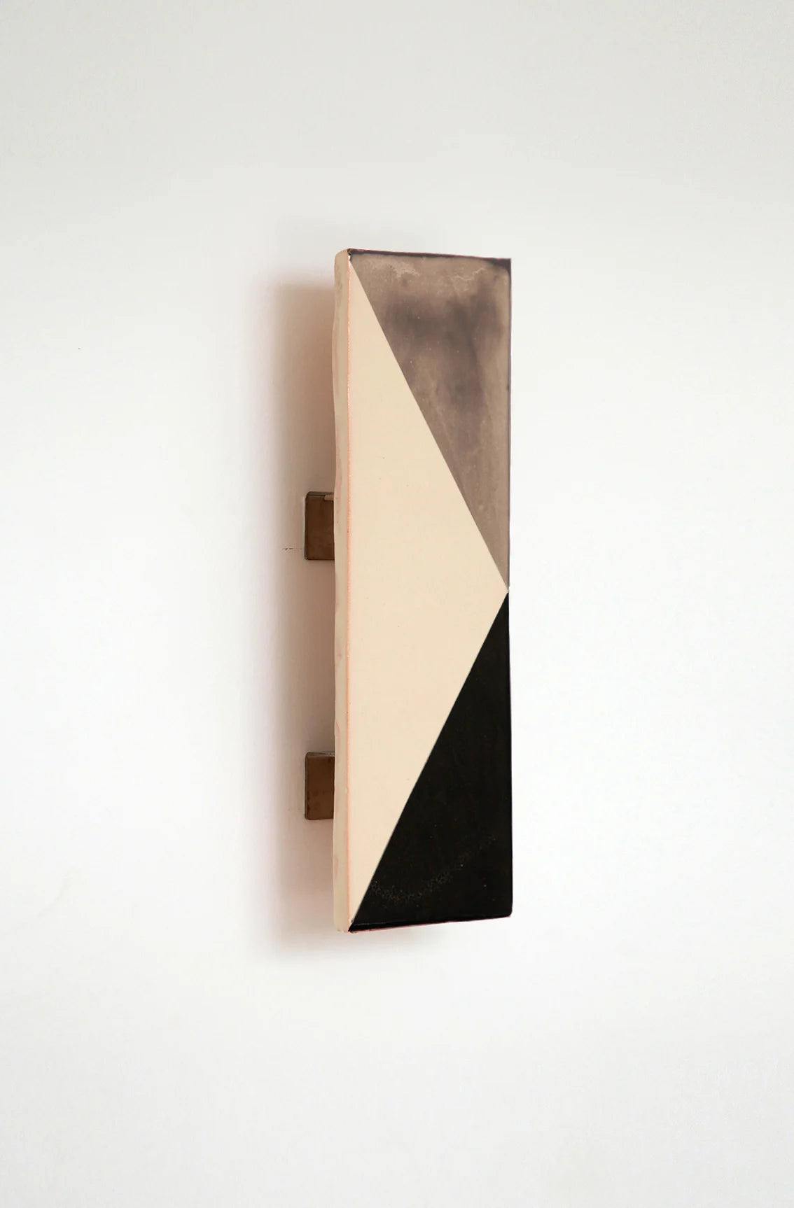 Wall-mounted light fixture by Violaine d'Harcourt with the light off. The design is a geometric pattern in grey, black and white.