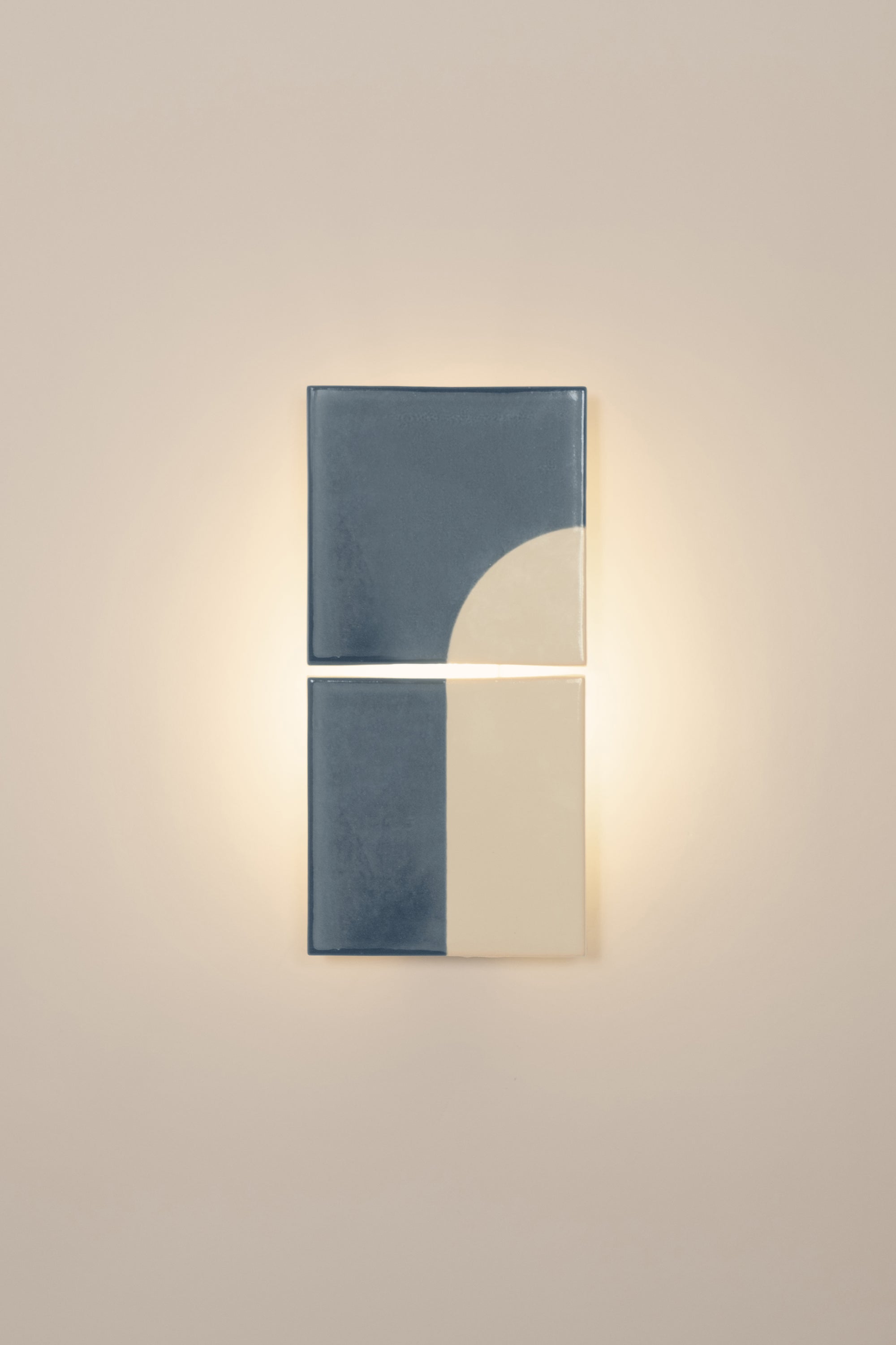 Wall-mounted light fixture by Violaine d'Harcourt with the light on. The design is a geometric pattern in blue and white with a neutral background.