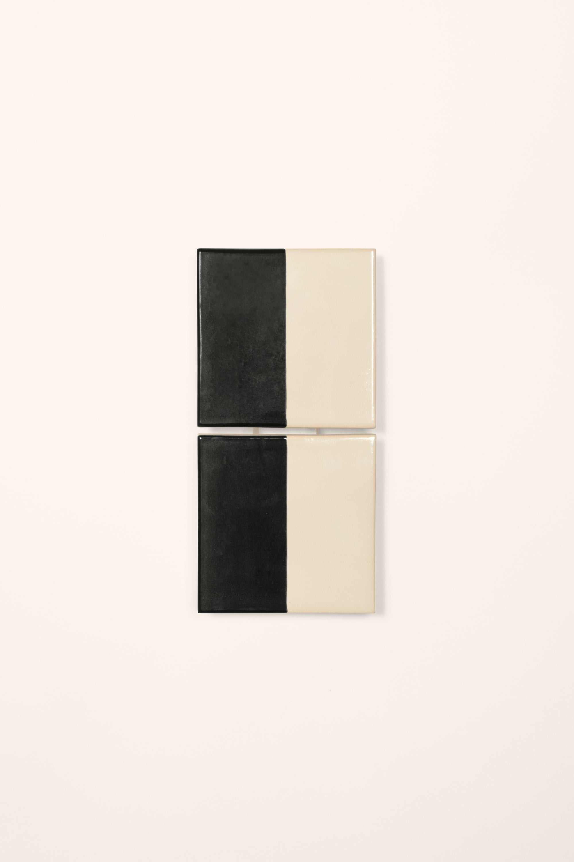 Wall-mounted light fixture by Violaine d'Harcourt with the light off. The design is two titles, half black and half white on a neutral background.