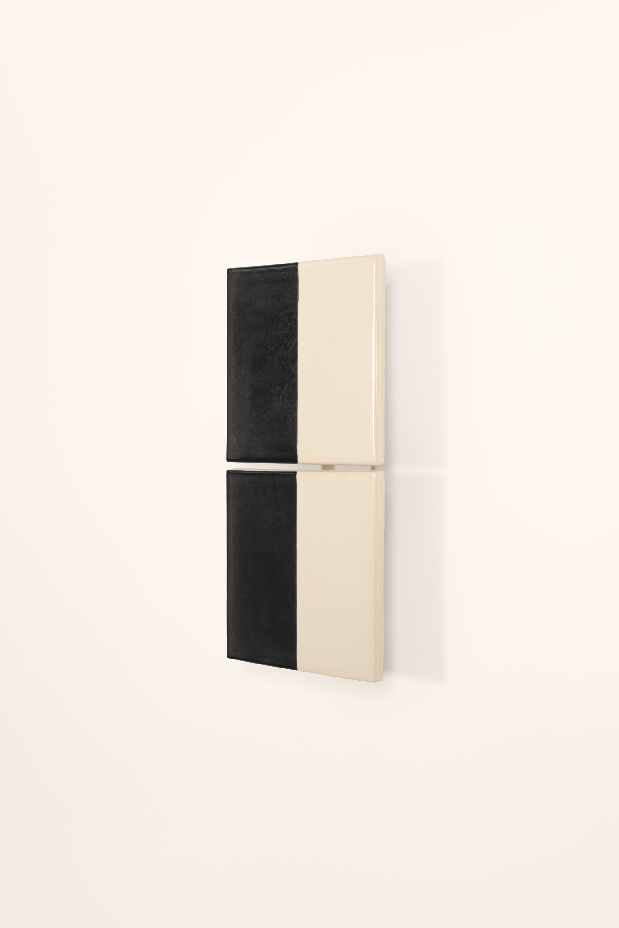 Wall-mounted light fixture by Violaine d'Harcourt with the light off. The design is two titles, half black and half white on a neutral background.