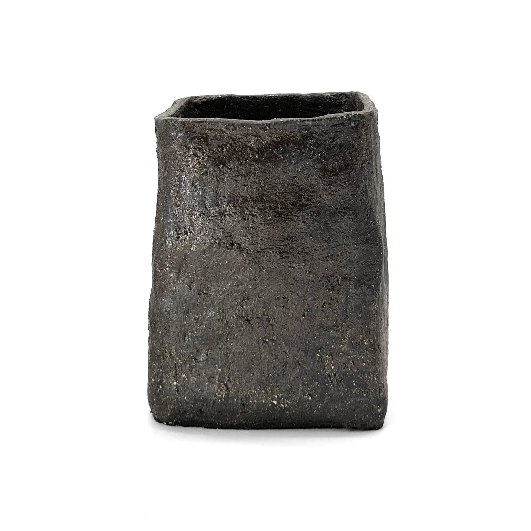 Textured, charcoal cubed vase by klangnapha on a white plinth with a neutral background.